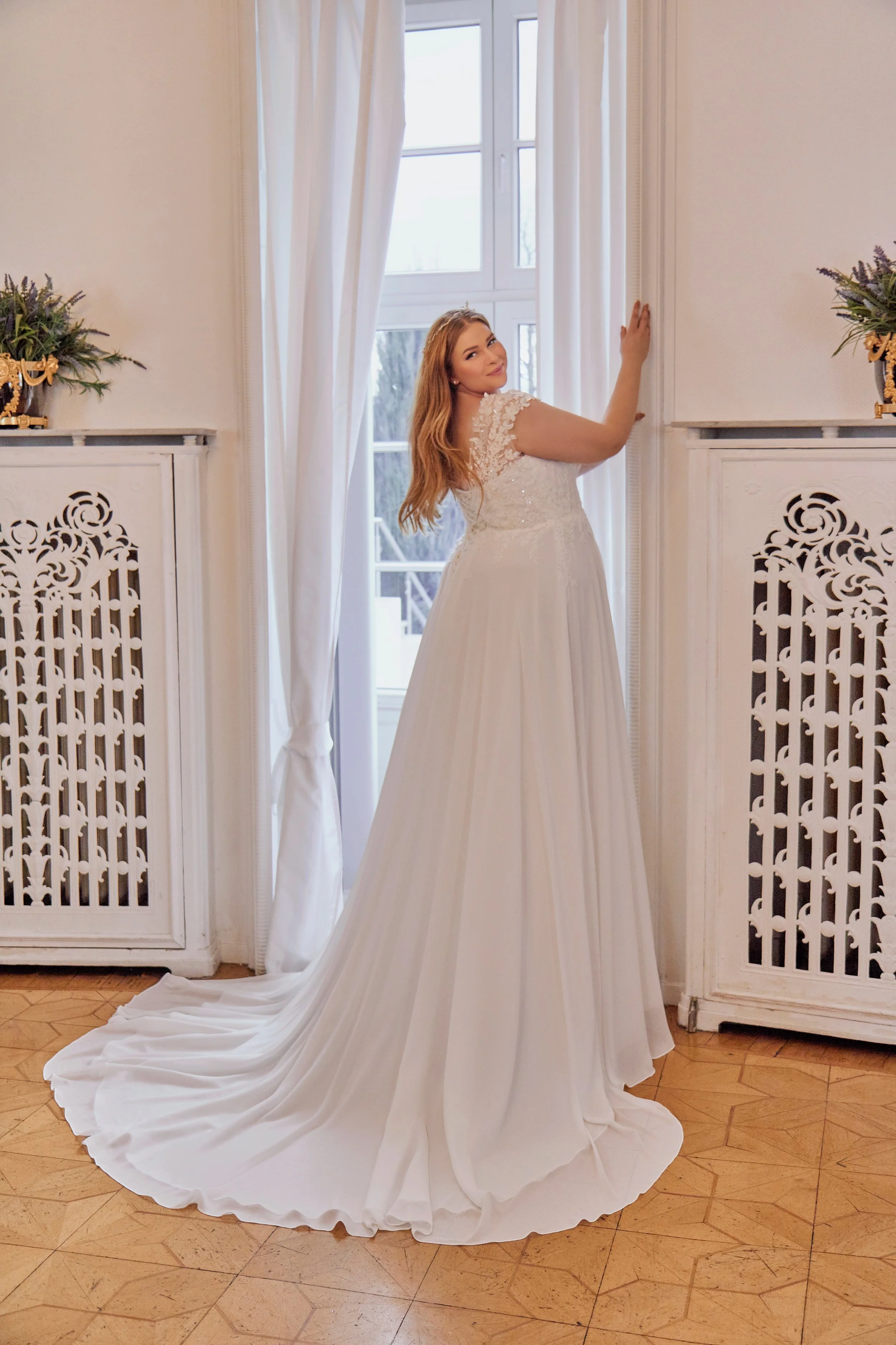 Back view of Lia Bella Model Tracy showing the floral lace shoulders, V-shaped back and wide flowing chiffon chapel train.