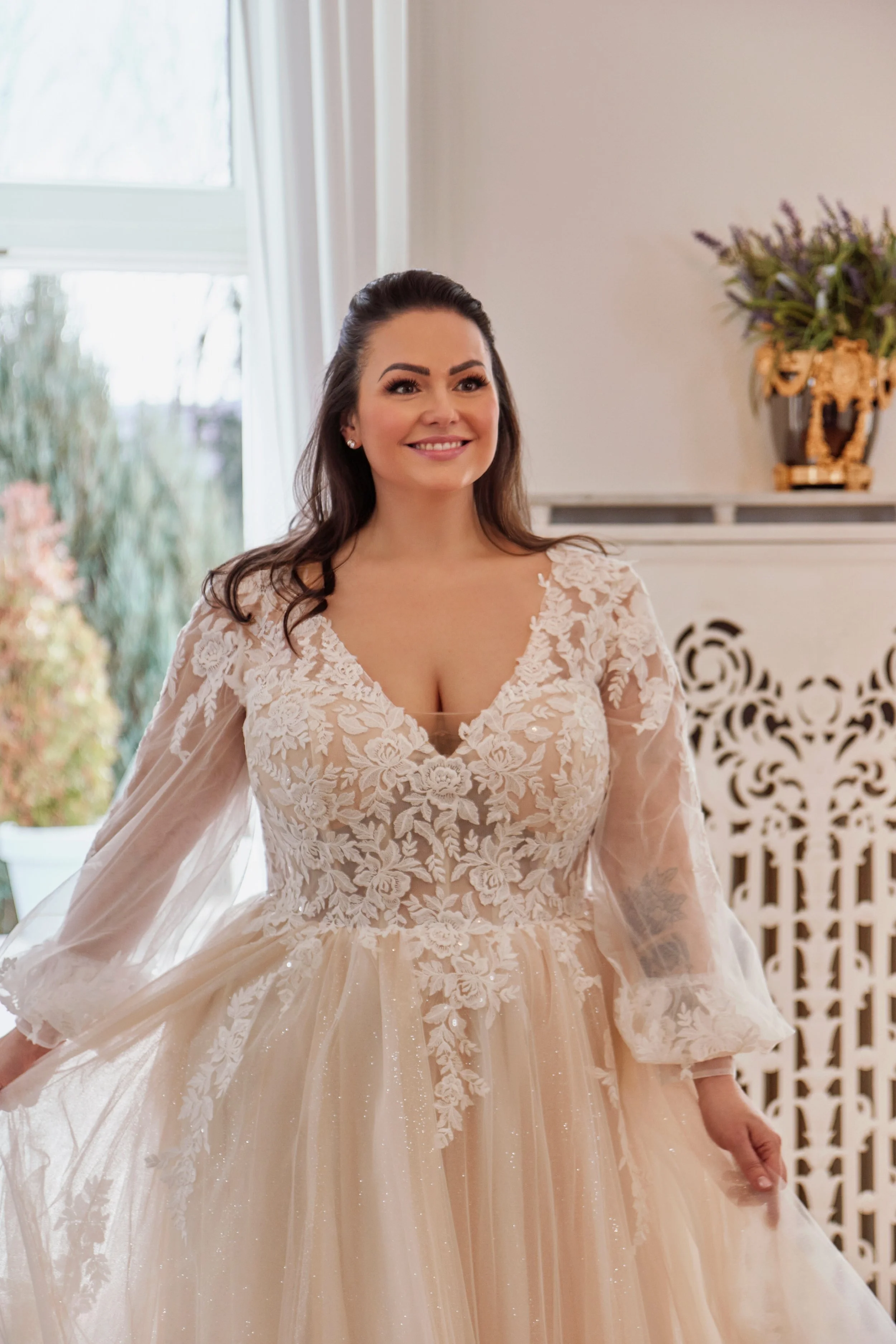 Close-up of Lia Bella Model Tiede highlighting the deep V-neckline, floral lace illusion bodice and transparent sleeves.