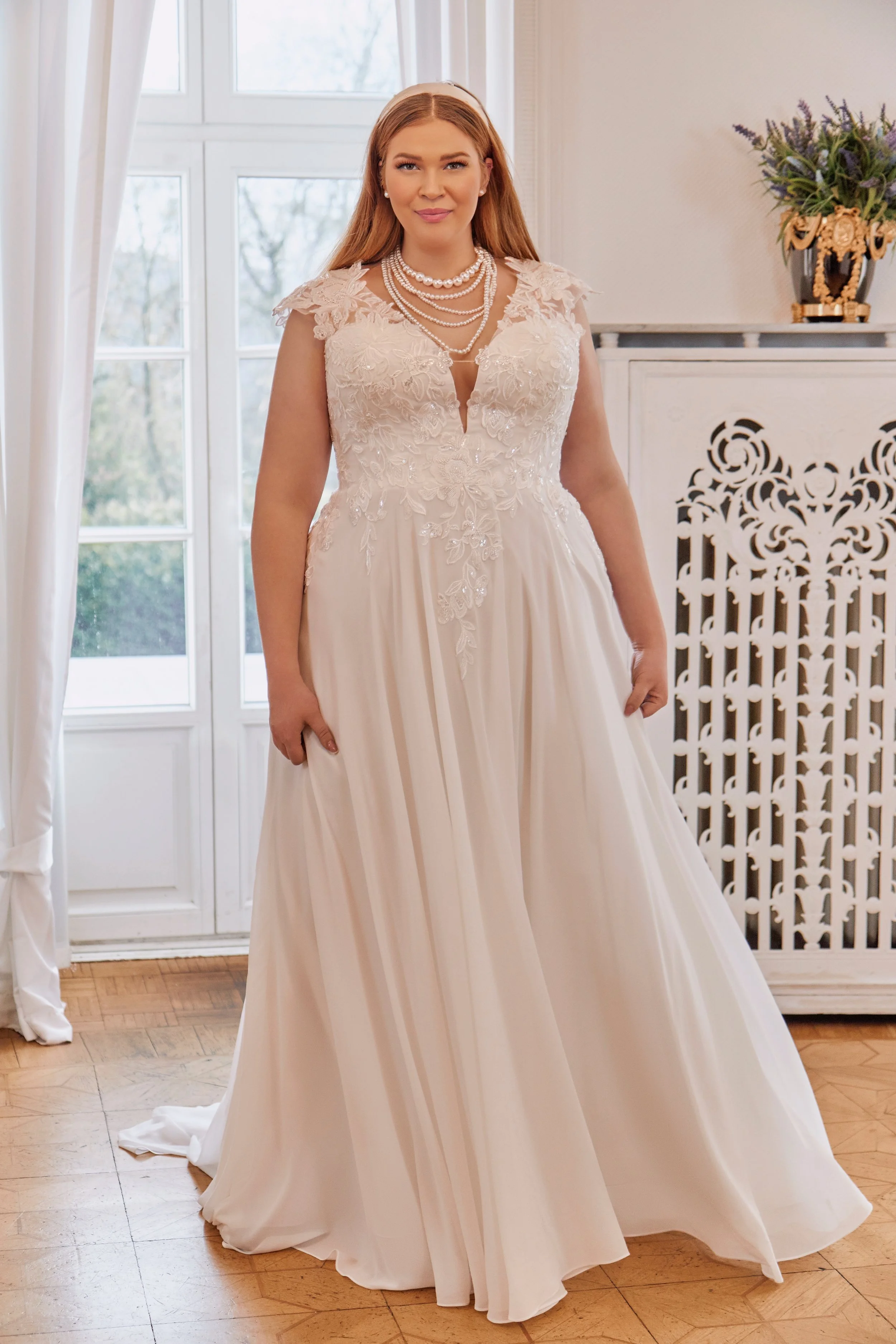 Full front view of Lia Bella Model Trixie, a curvy A-line wedding dress with a deep V-neckline, floral lace bodice and flowing chiffon skirt.