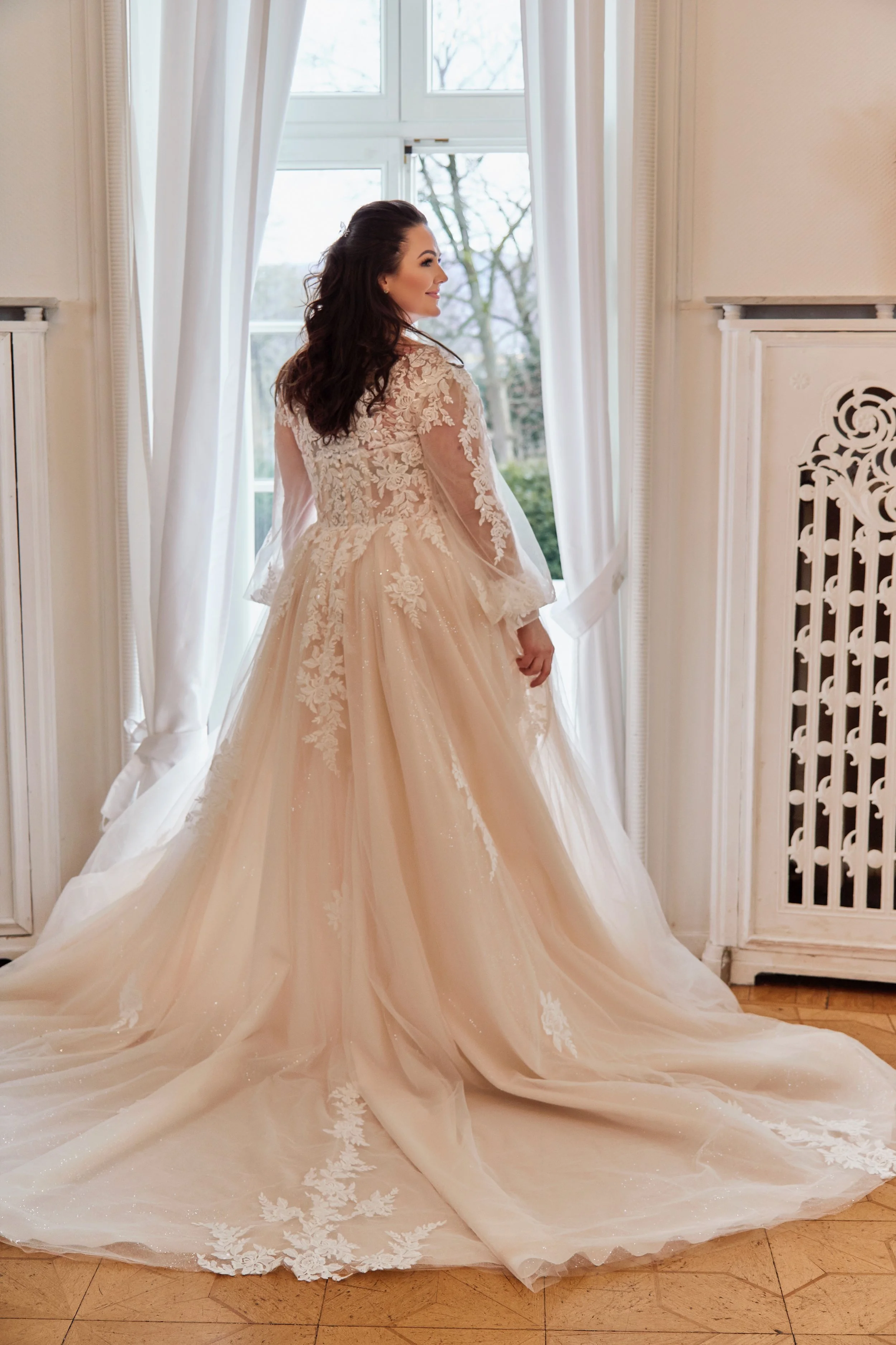Back view of Lia Bella Model Tiede showing the illusion lace bodice and wide glitter-tulle chapel train with floral appliqués.