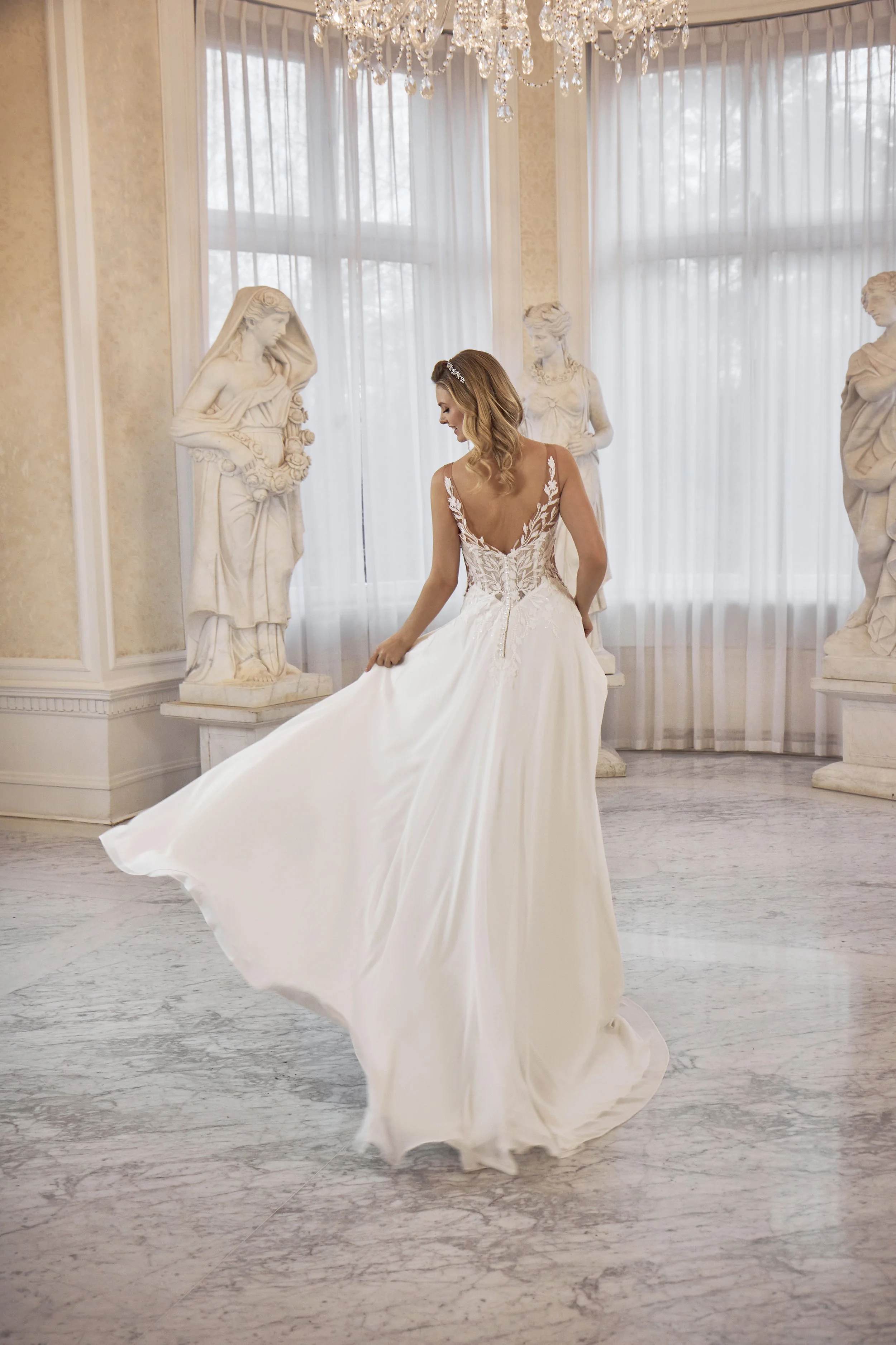 Back view of Lia Bella Model Talida showing the flowing chiffon A-line skirt and soft chapel train.