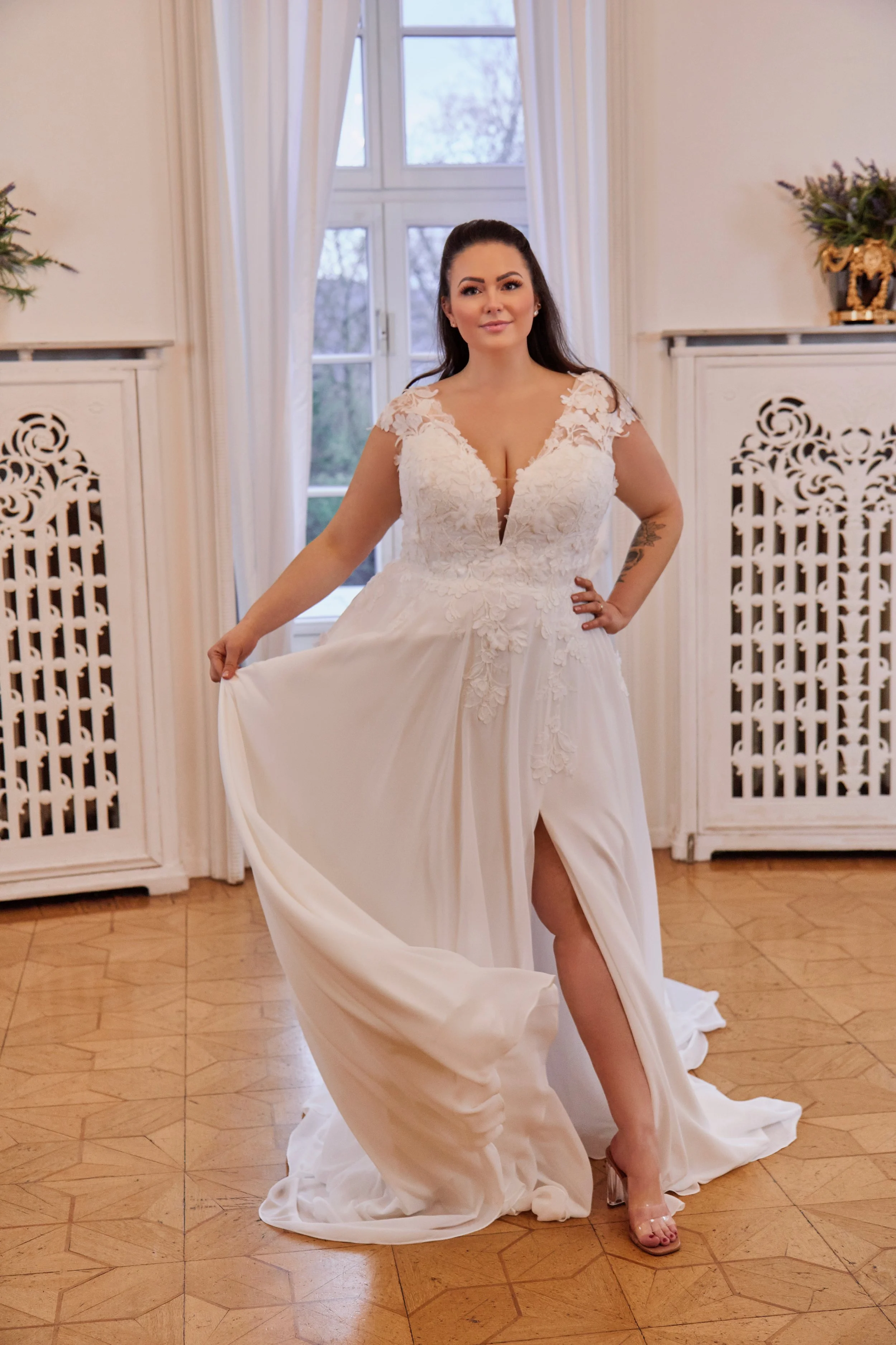 Full front view of Lia Bella Model Toya, a curvy A-line wedding dress with a floral lace bodice, flowing chiffon skirt and high slit.