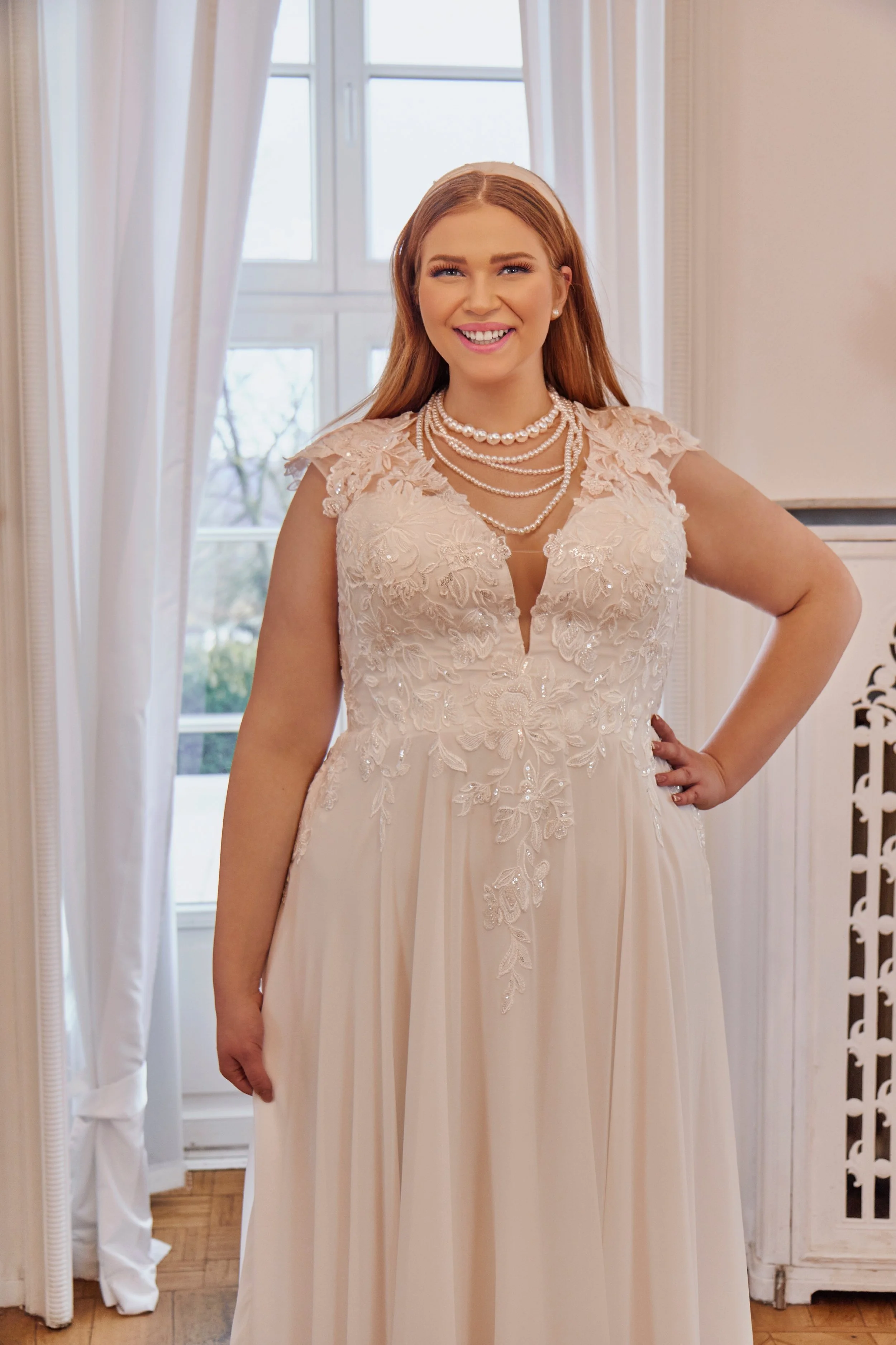 Close-up of Lia Bella Model Trixie highlighting the deep V-neckline, beaded floral lace bodice and delicate lace cap sleeves.