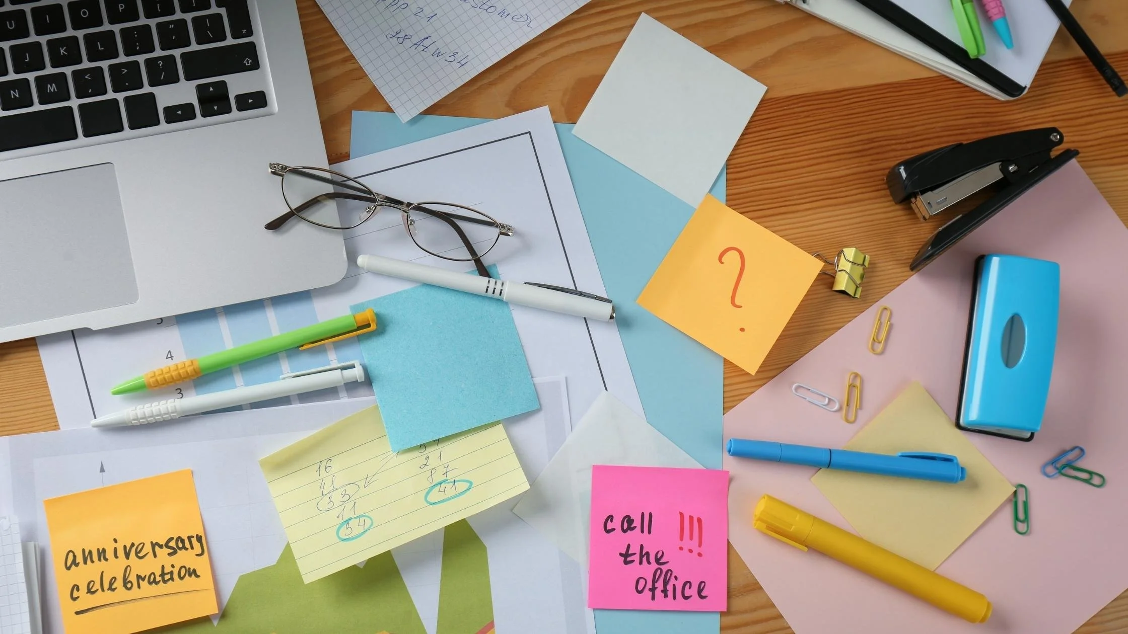 Messy desk with papers and laptop representing digital clutter and the need to tidy a Squarespace website backend
