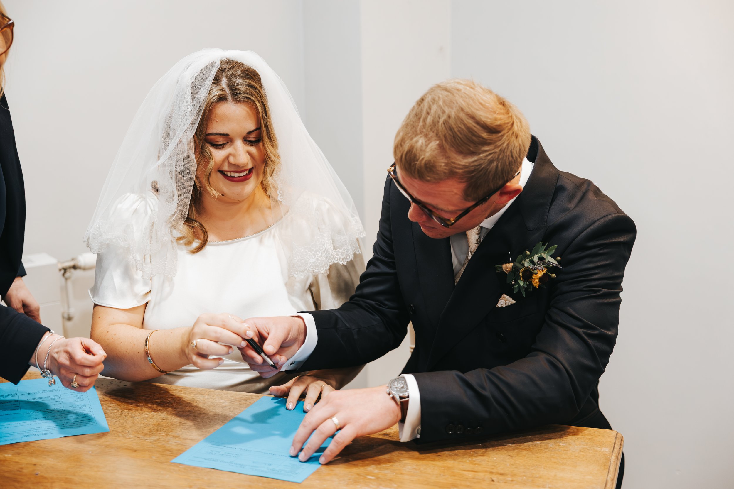 A bride and groom signing a marriage certificate during their wedding ceremony.