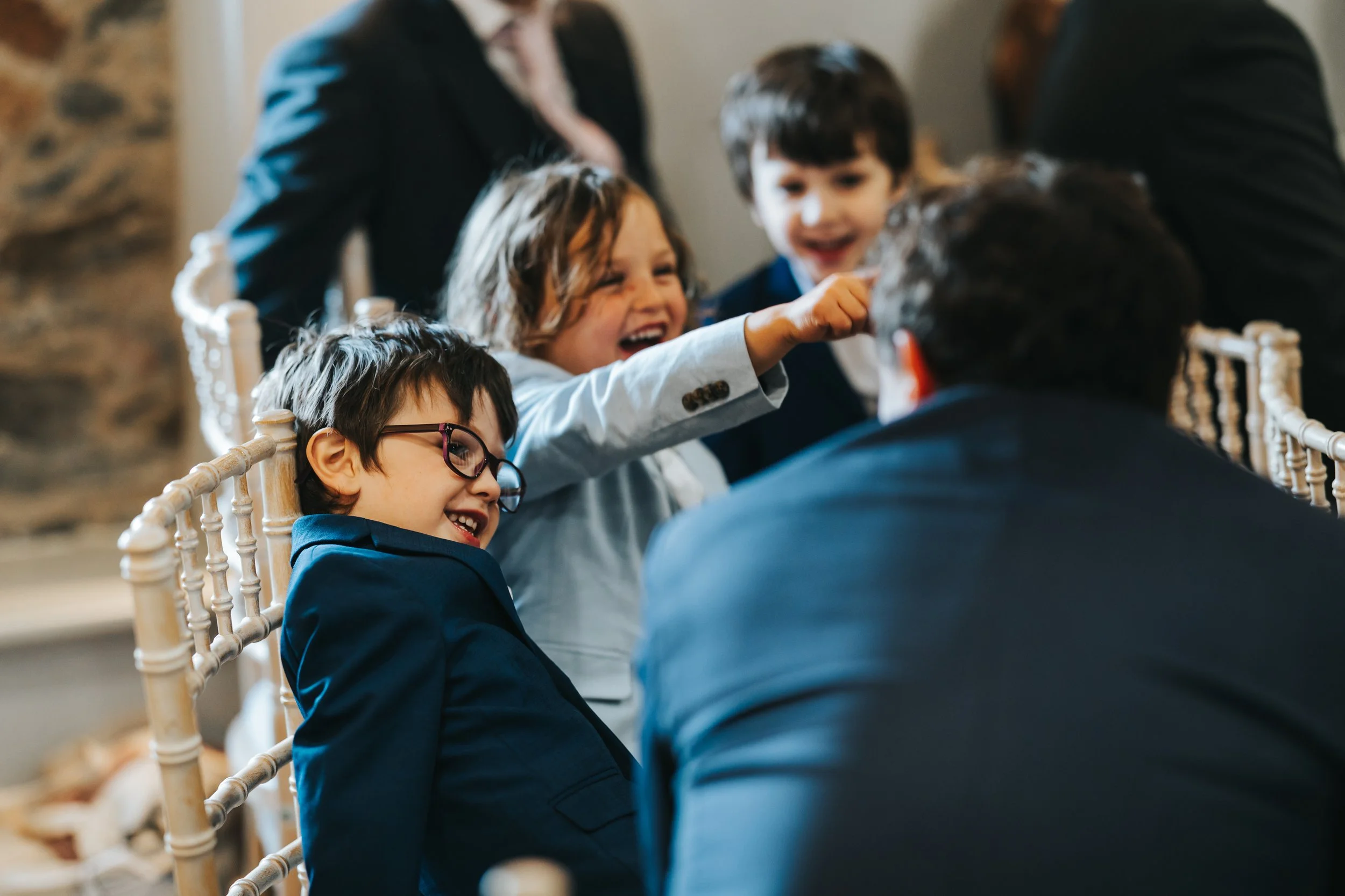 Children and adults seated at a table, engaging in playful conversation, with some children smiling and talking animatedly.