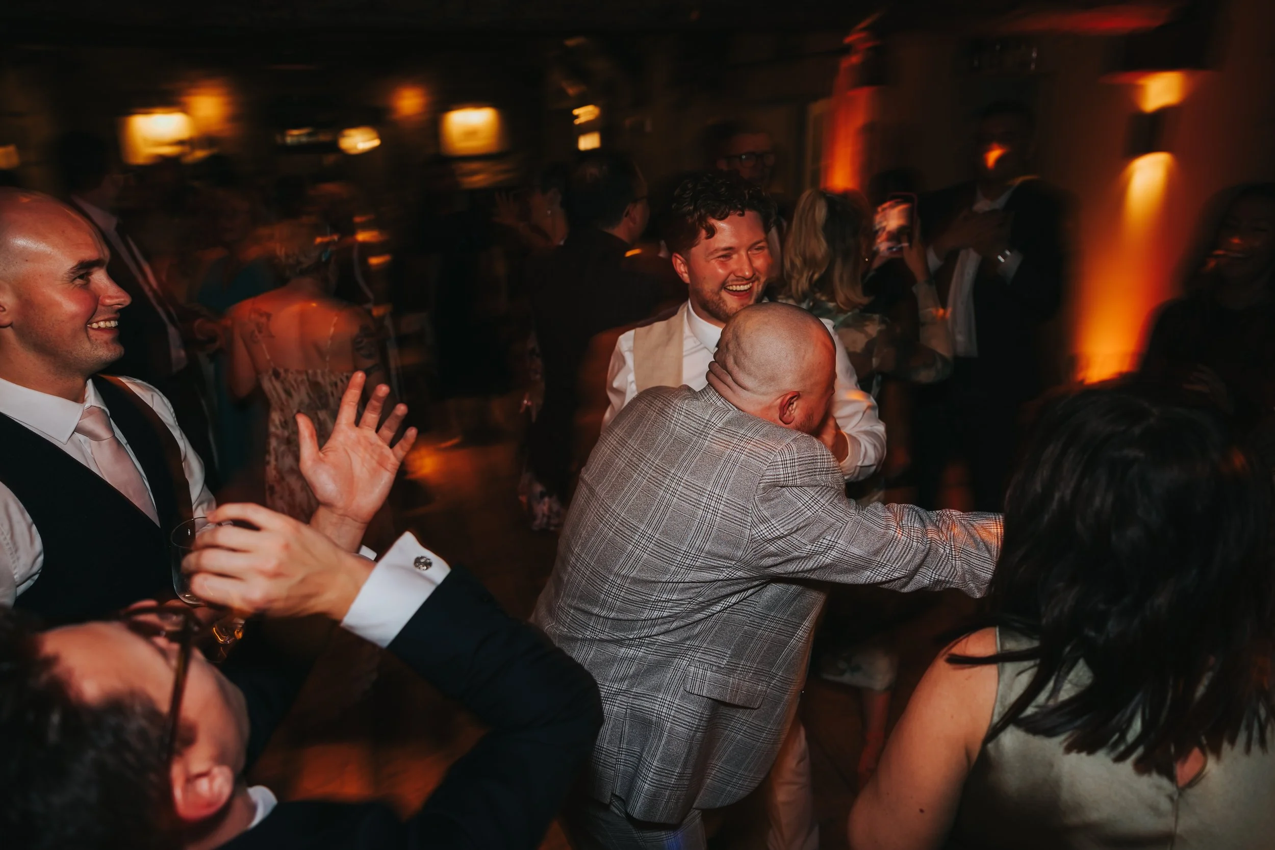 People dancing and celebrating at a lively indoor event with warm lighting, smiling and enjoying themselves.