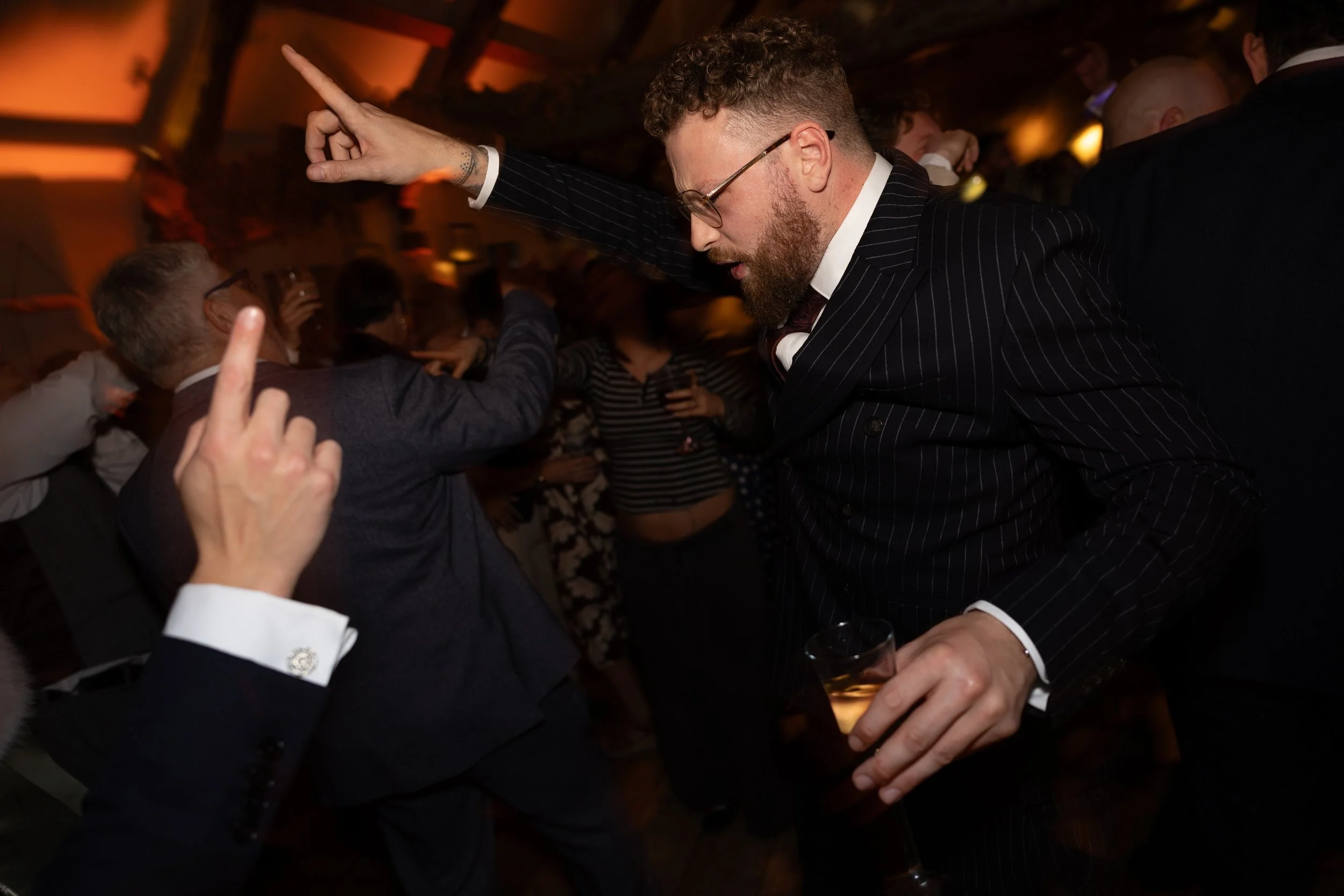 People dancing and socializing at a party or nightclub, with dim lighting and a lively atmosphere.