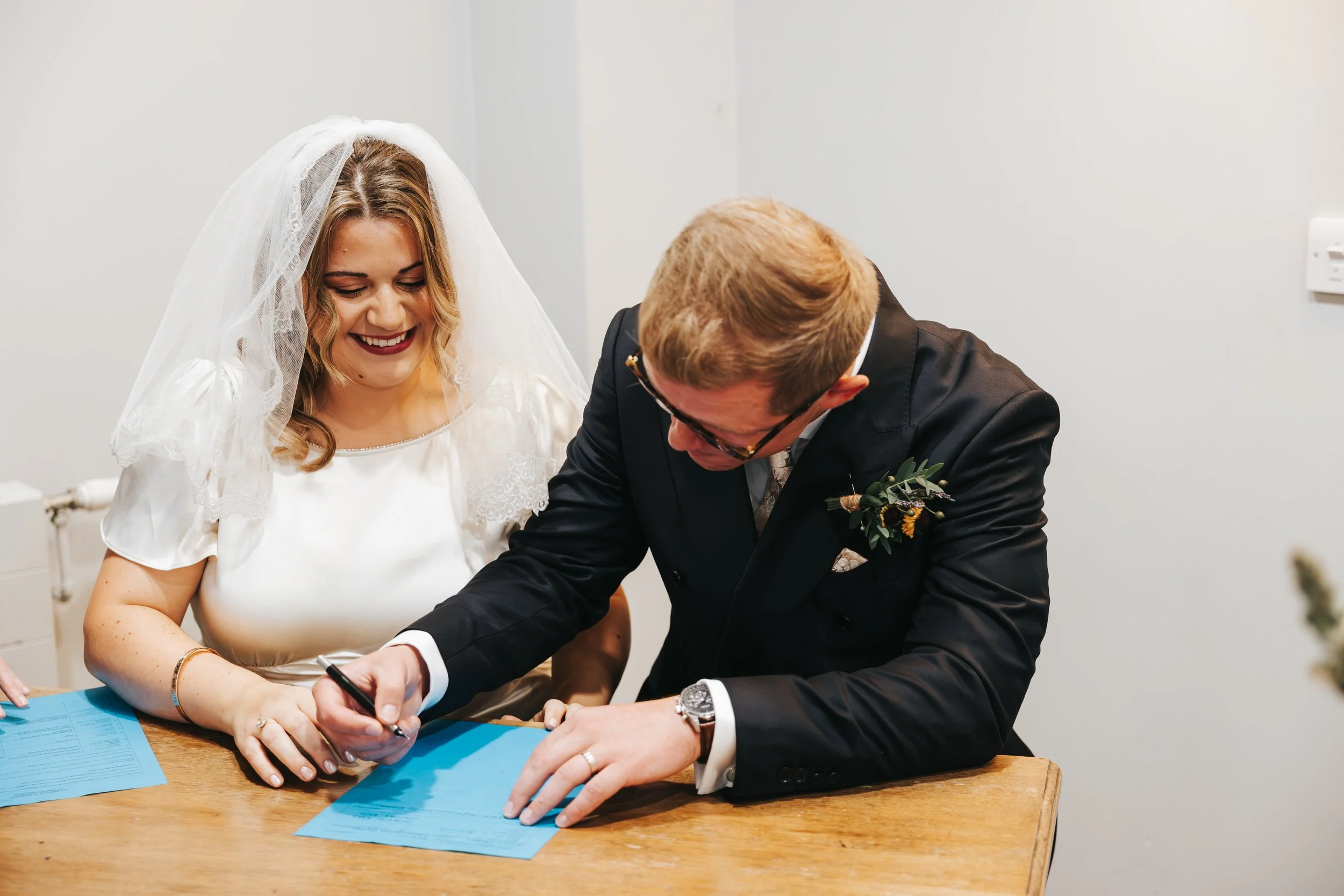 Bride and groom signing marriage license at wedding ceremony.