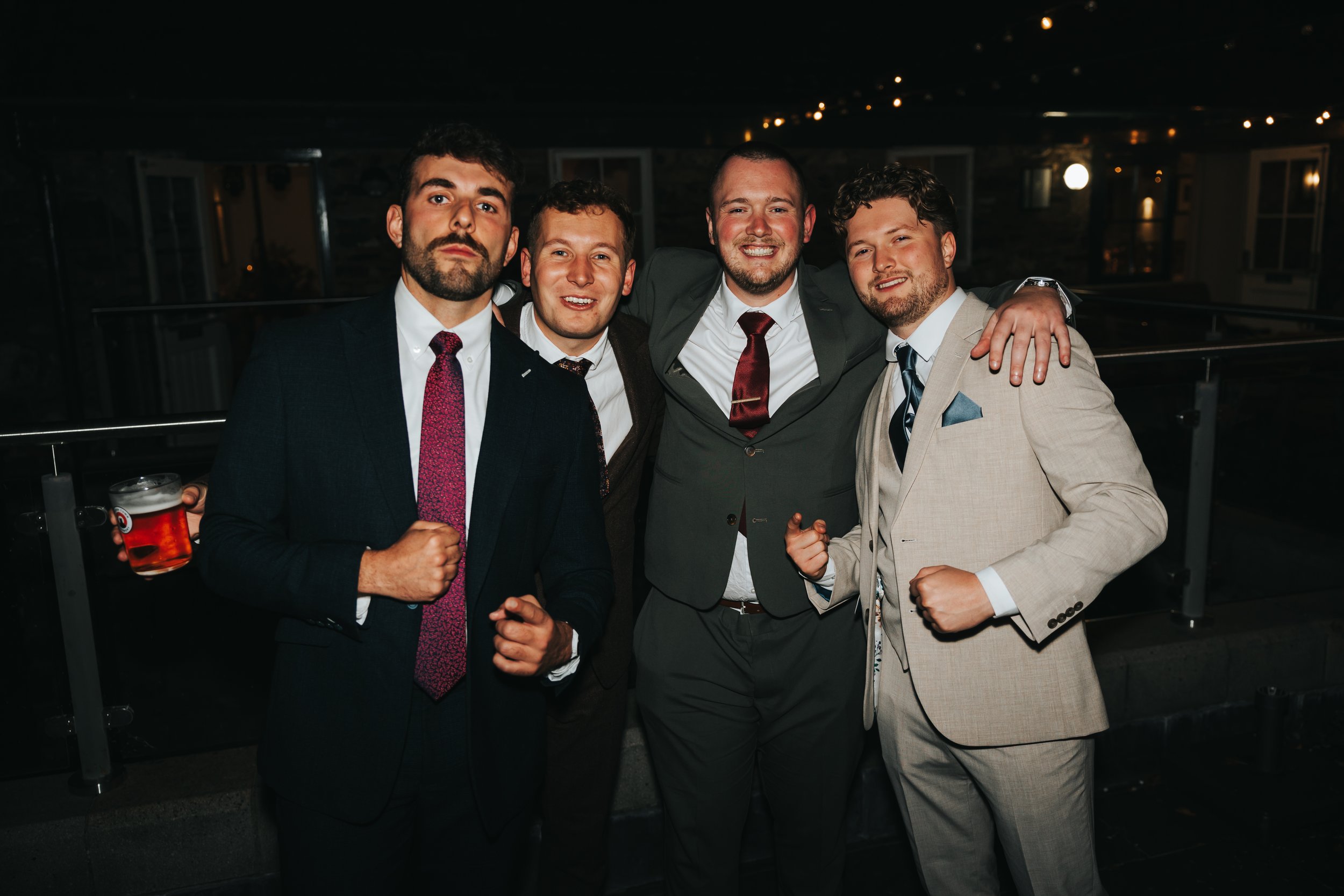 Five men in suits celebrating at a nighttime event, smiling and showing fists.
