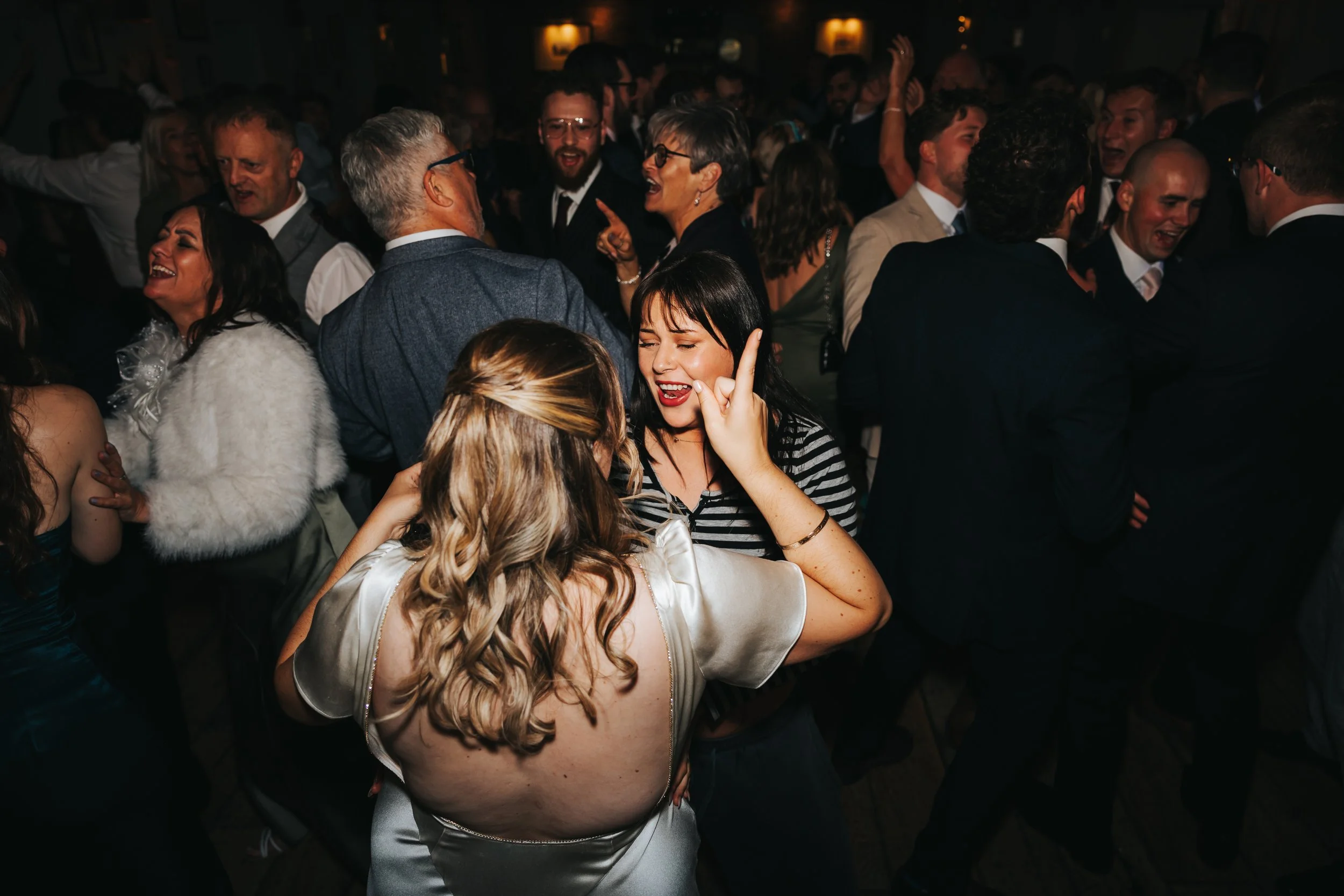 People dancing and socializing at a lively party or event in a dimly lit venue.