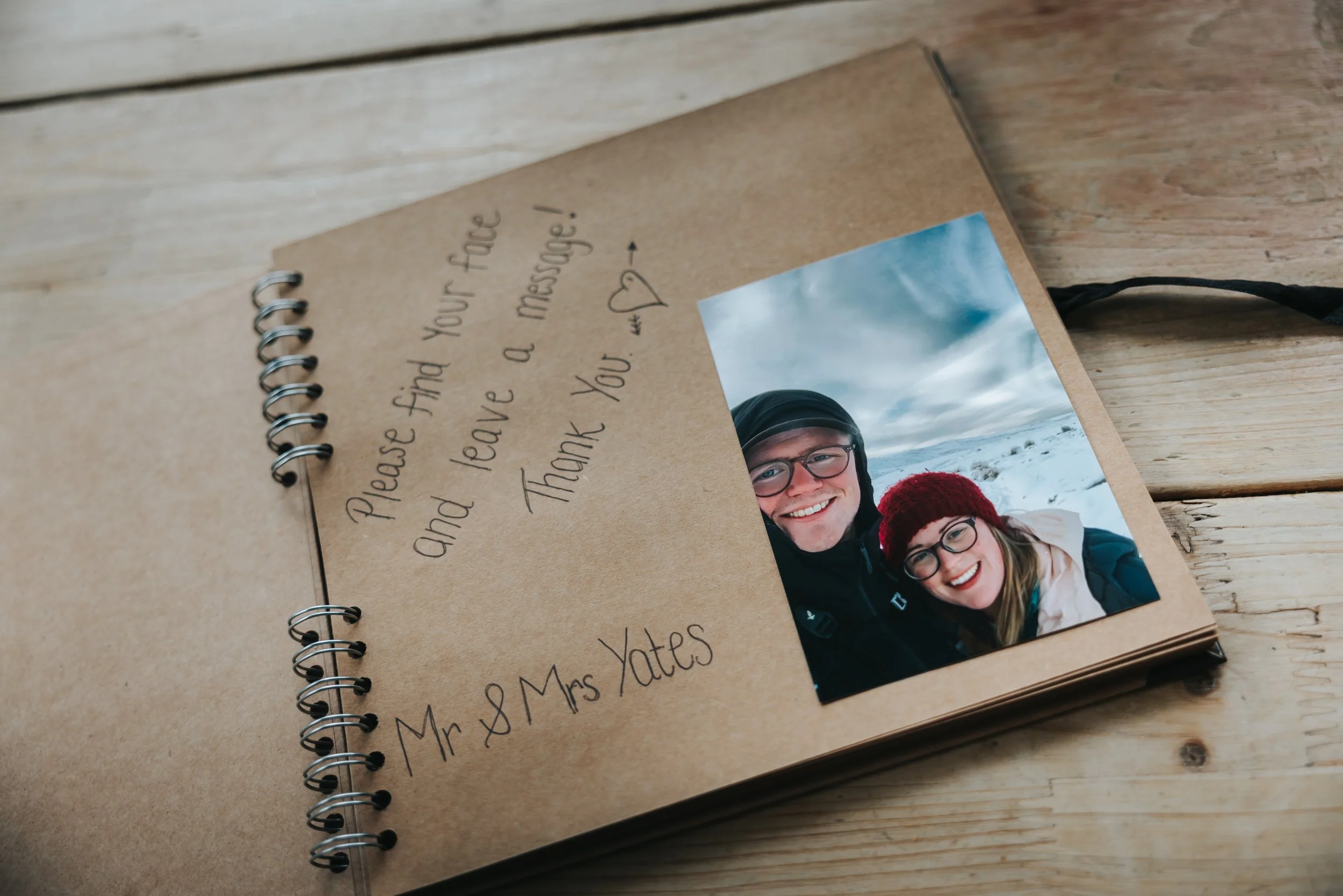 A scrapbook page with a handwritten message and a photo of a smiling man and woman in winter gear outdoors.
