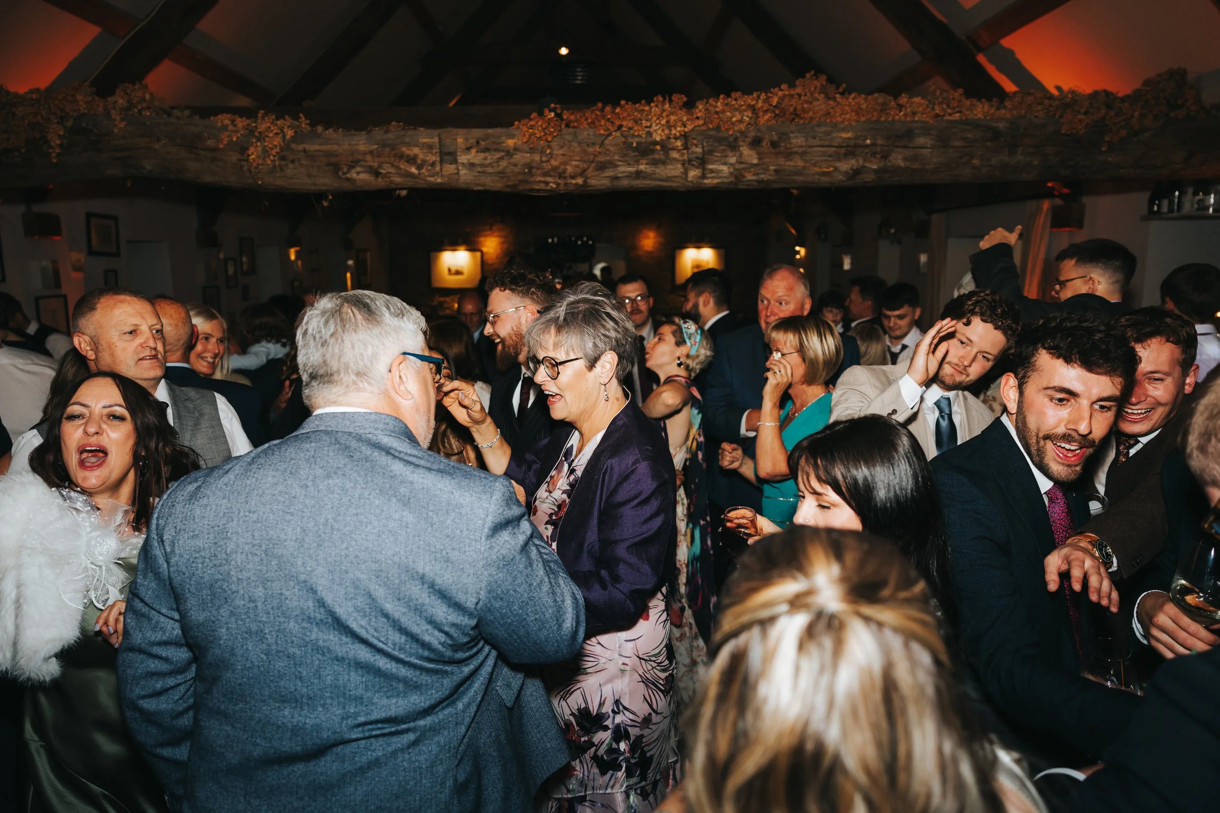 Crowd of people dancing and socializing at a lively indoor celebration or party.