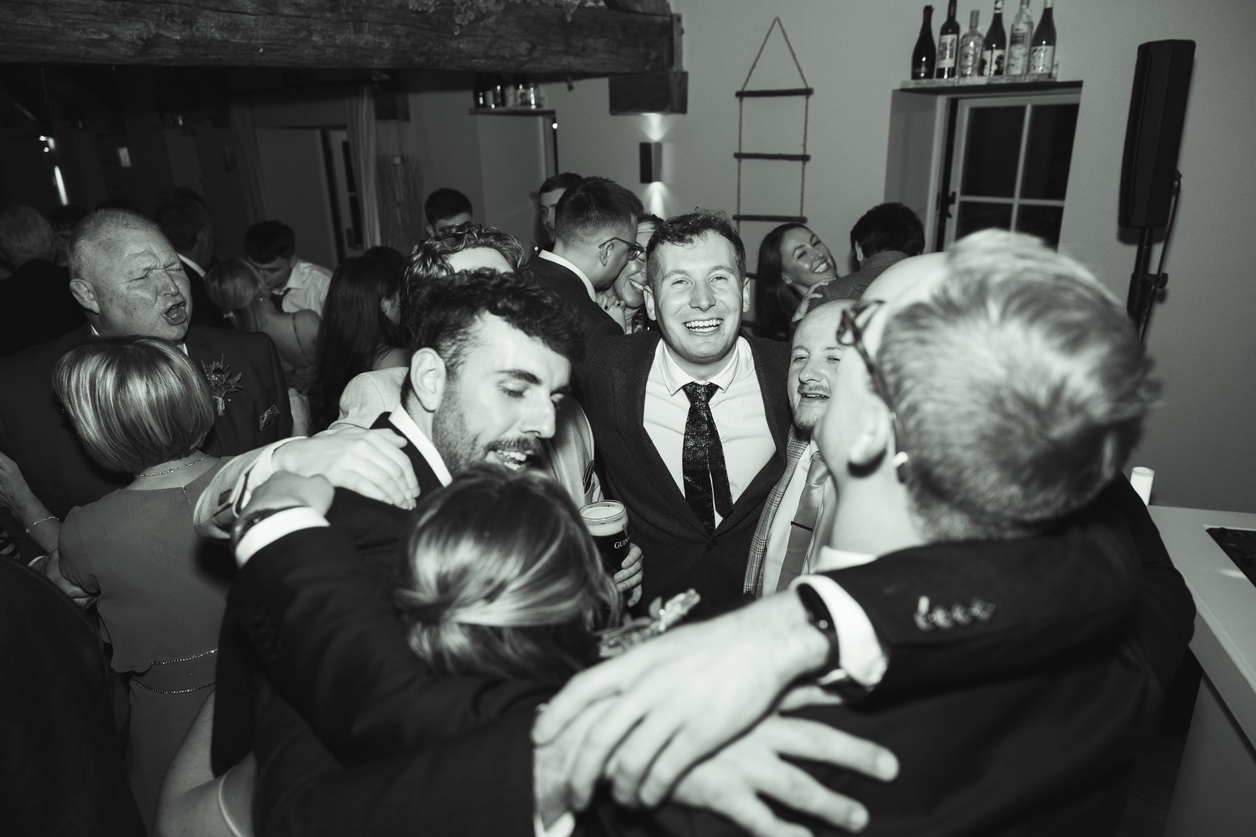 Group of people celebrating and enjoying themselves at a party, smiling and hugging each other.