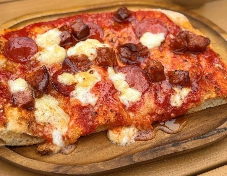 A slice of pepperoni pizza with melted cheese on a wooden pizza board.