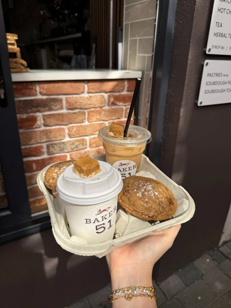 Tray with two cups of coffee, two cookies, and an iced coffee outside a bakery or café.