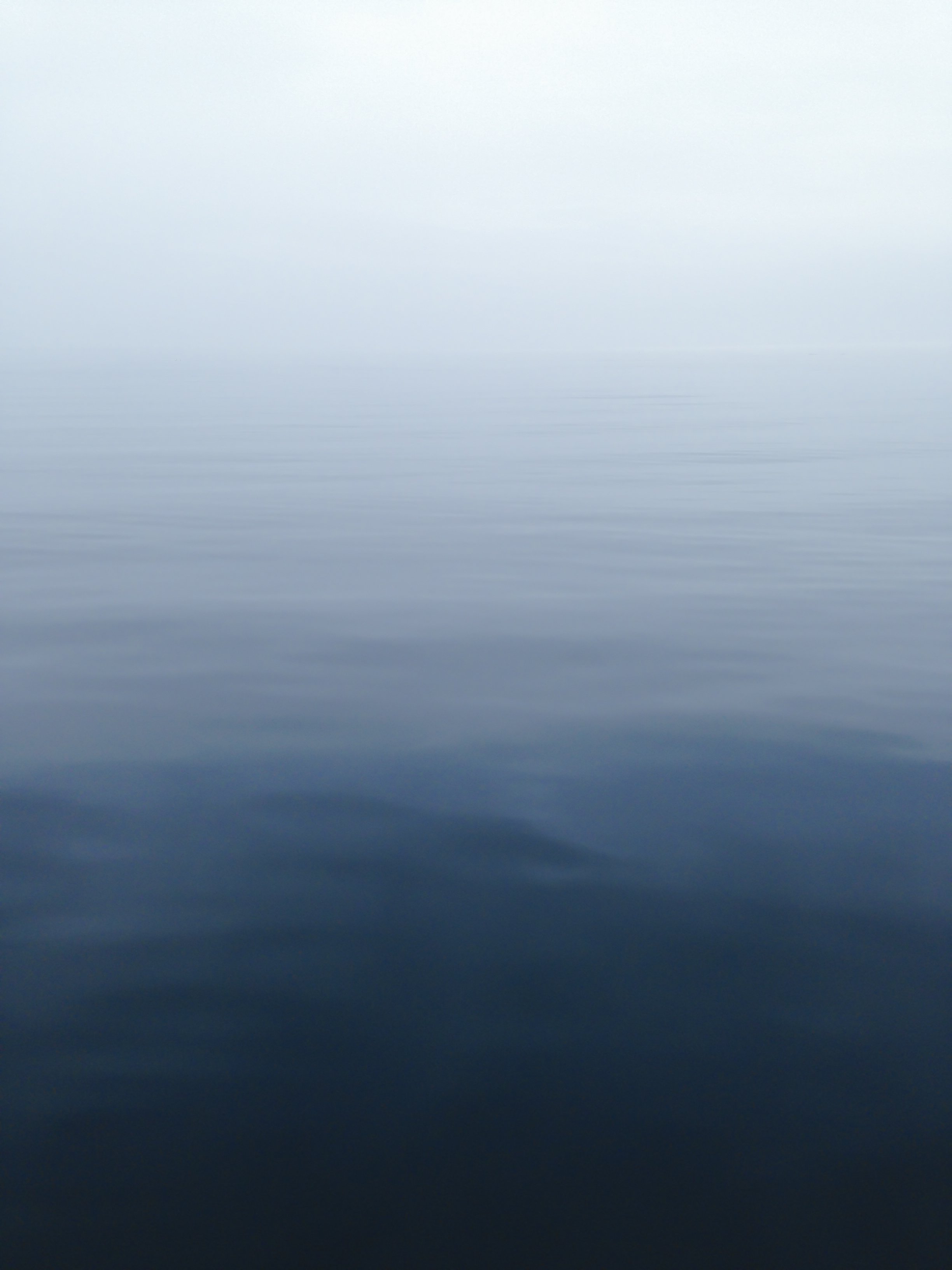 Soft fog over a calm ocean horizon in muted blue tones