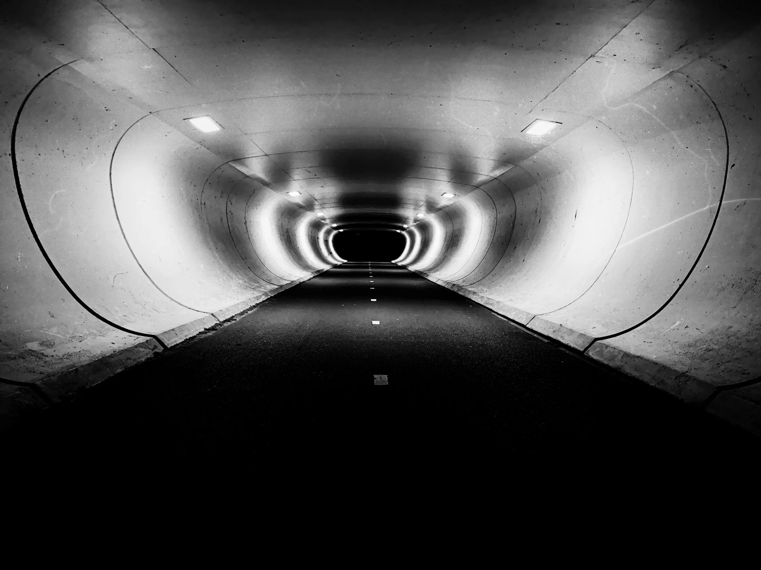 Black and white tunnel with road stretching into darkness