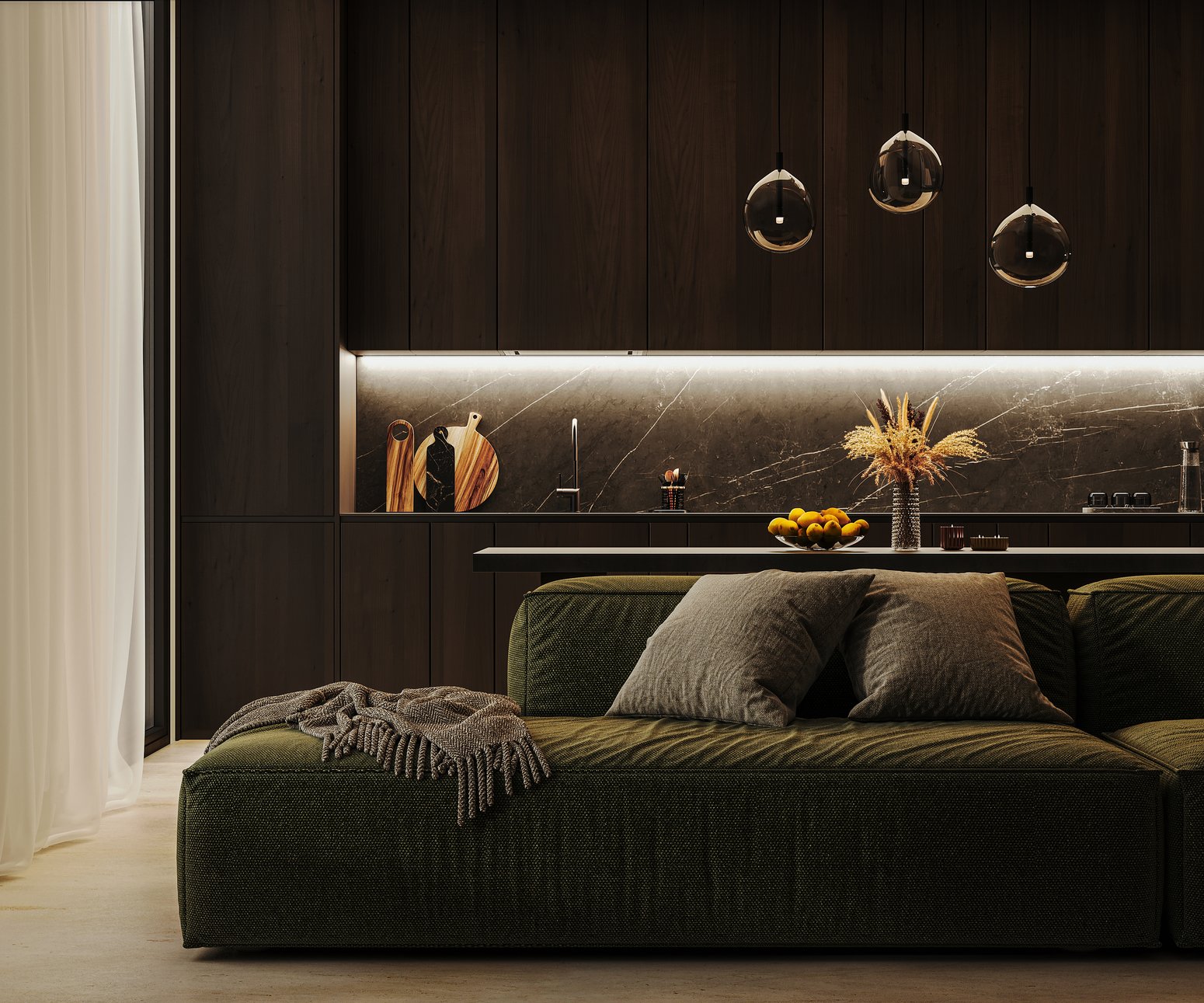 A green sectional sofa with a throw blanket in a dimly lit modern living room, kitchen visible in the background, late evening