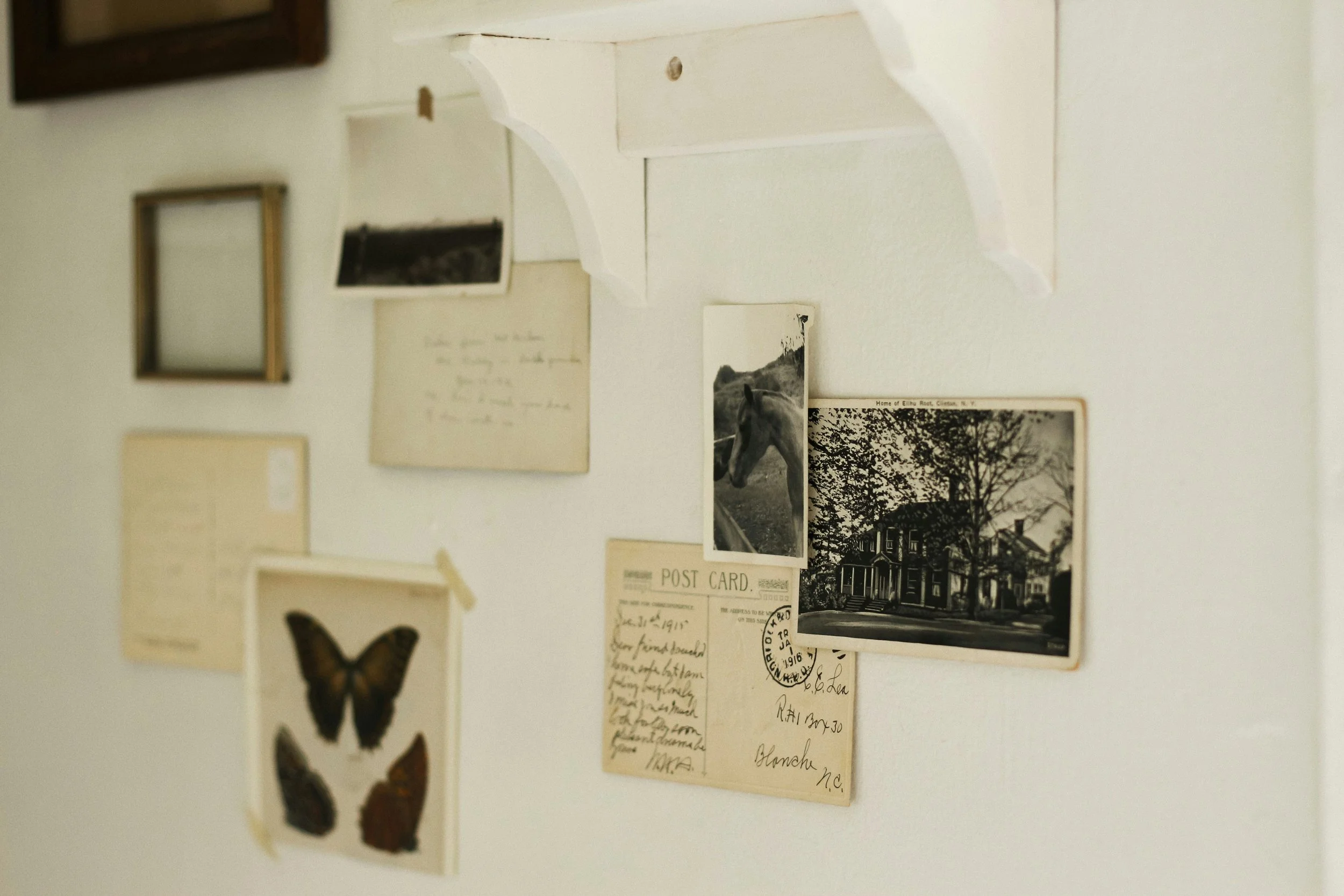 Vintage postcards, photographs, and handwritten notes displayed on a wall