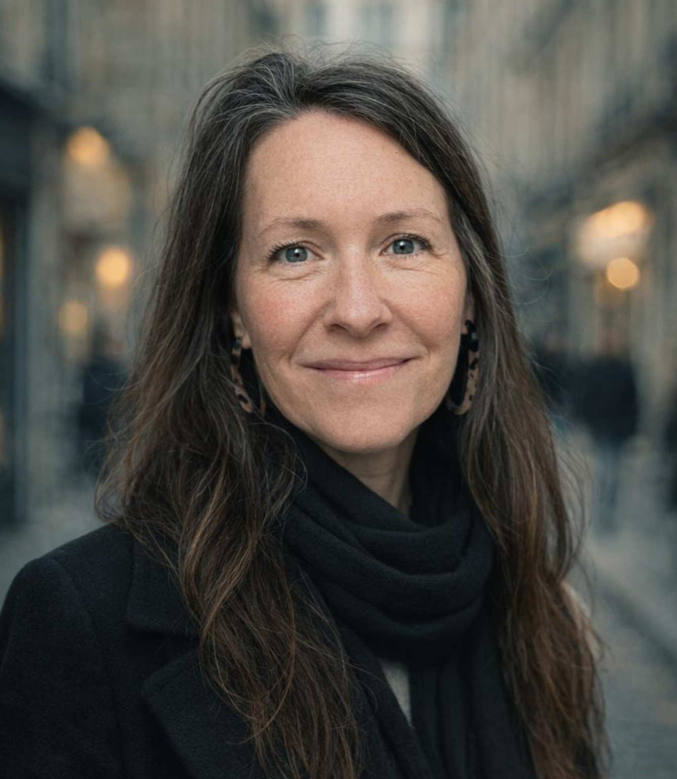 A woman with long brown hair wearing a white sweater with red and brown stripes, smiling at the camera.