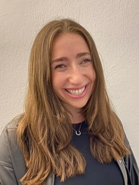 Dr. Julie Zeiberg, a psychologist woman with long, light brown hair, smiling, standing against a plain wall.