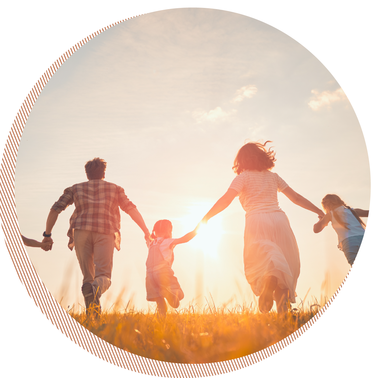 Family holding hands and running through a field at sunset.