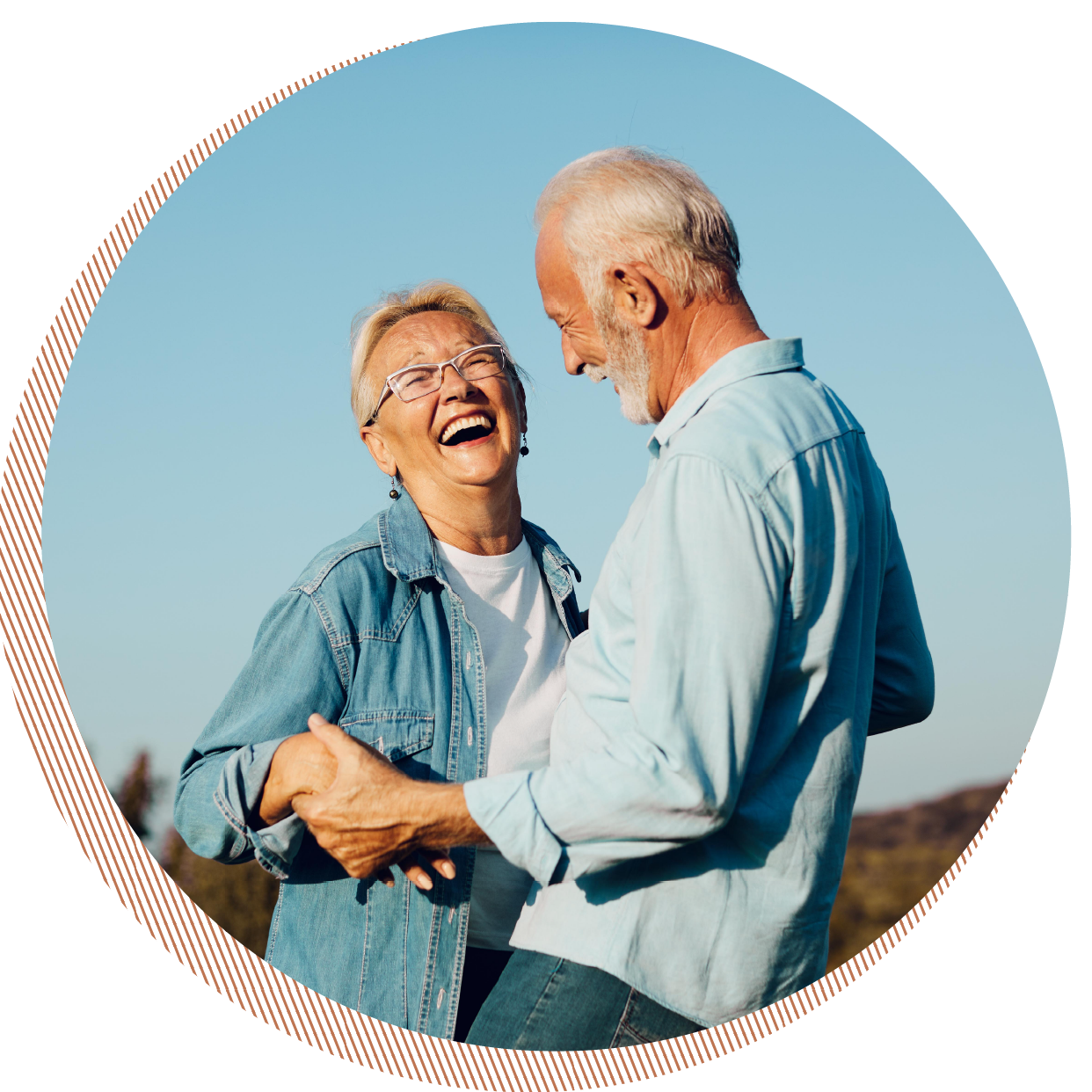 An elderly couple, smiling and laughing together outdoors against a clear blue sky, holding hands and looking happy.