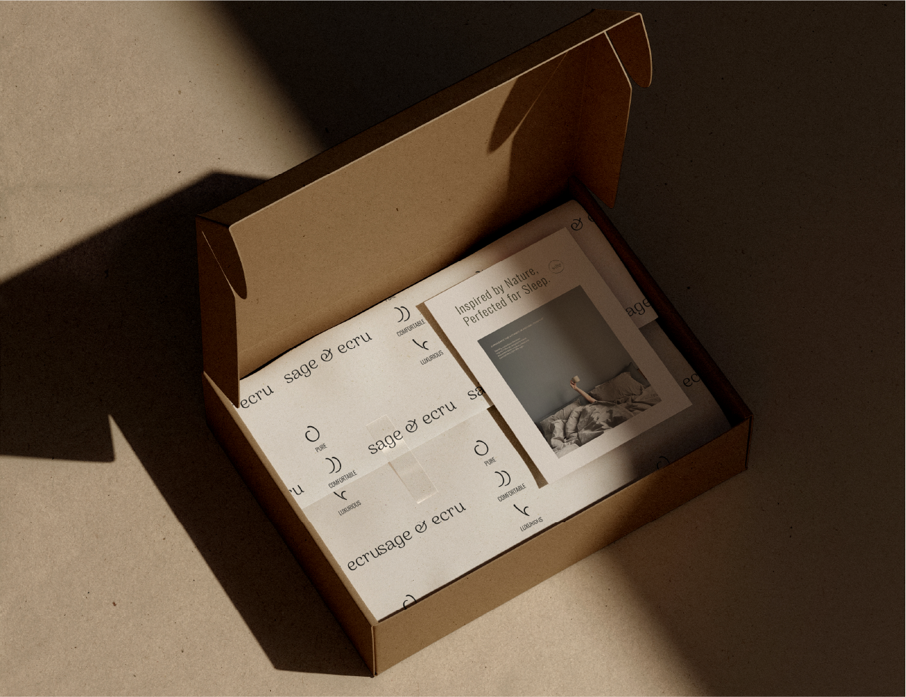 Open cardboard box containing a framed photograph of a person lying in bed and a sheet of paper with text about sleep.