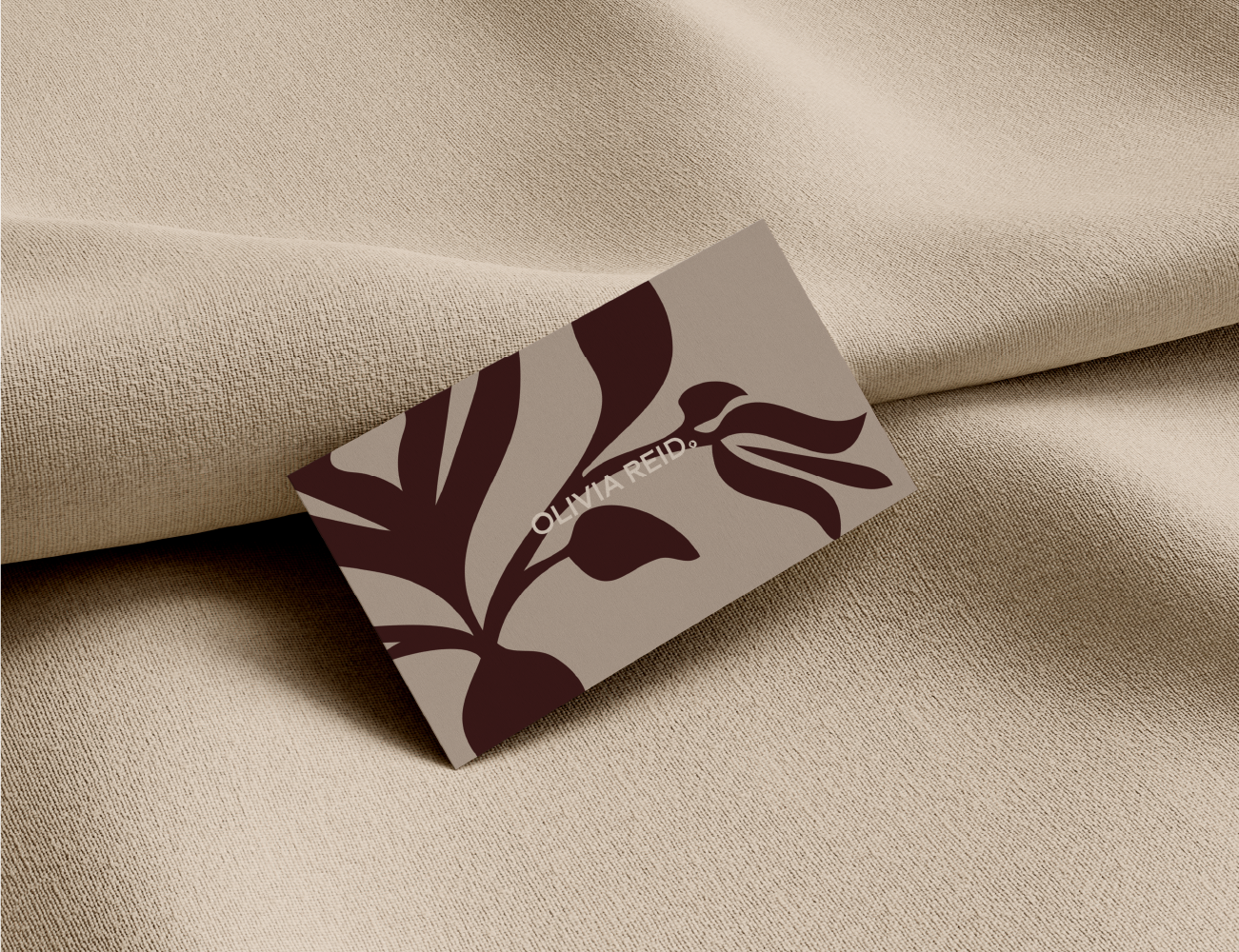 Place card with the name Olivia Reid on a beige fabric surface.