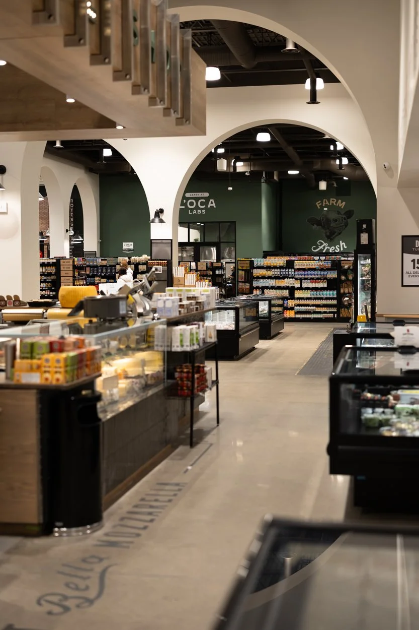 Inside a grocery store with various shelves stocked with food and products, checkout counters, and a green wall with the sign 'LOCA Labs' and images of farm-fresh food.