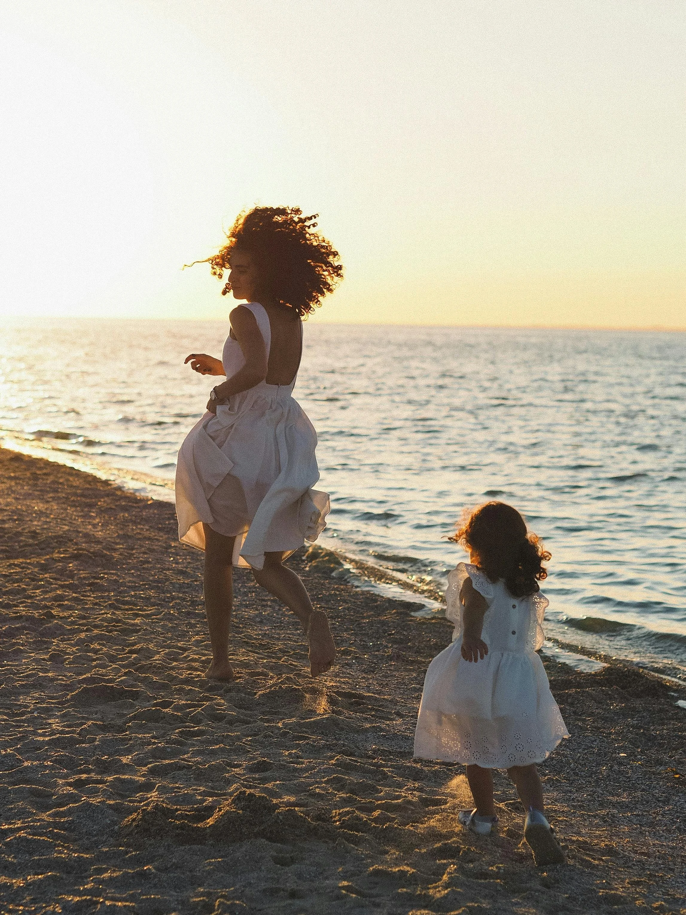 Young girl chasing her mom at the beach