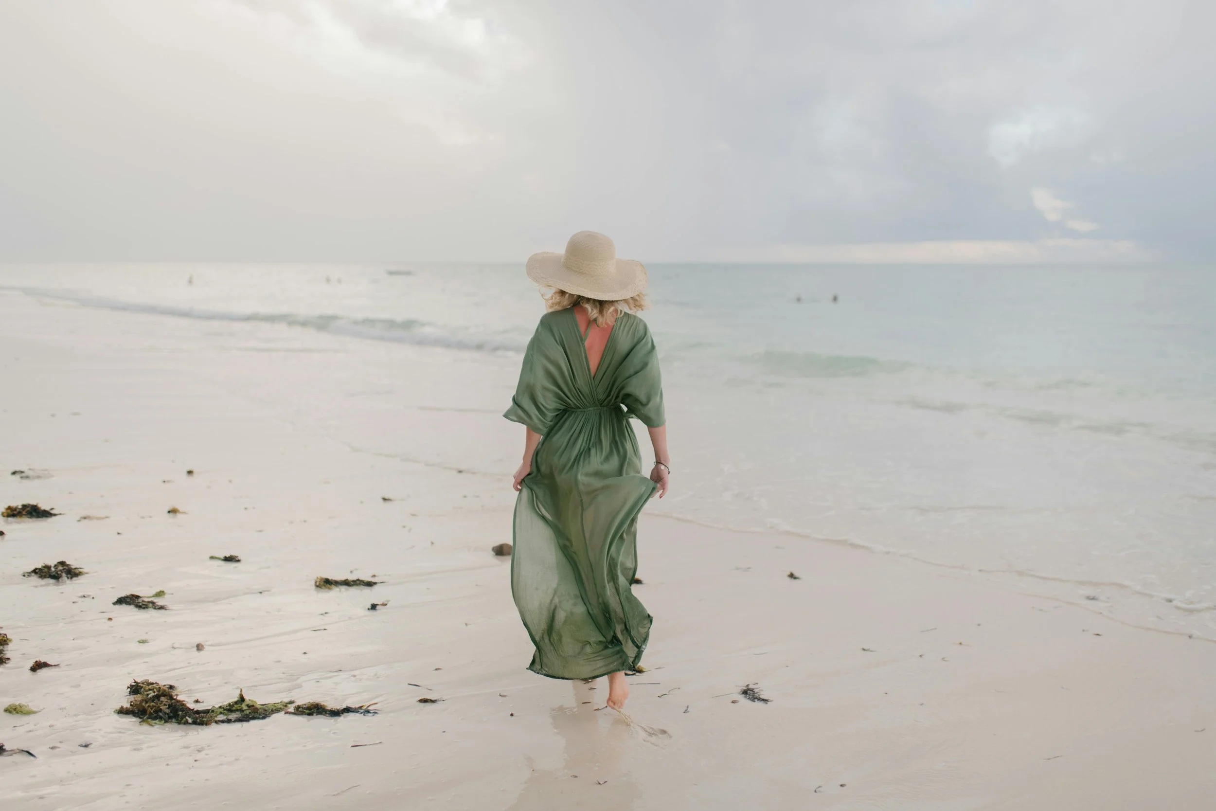 Woman in a green dress walking on the beach