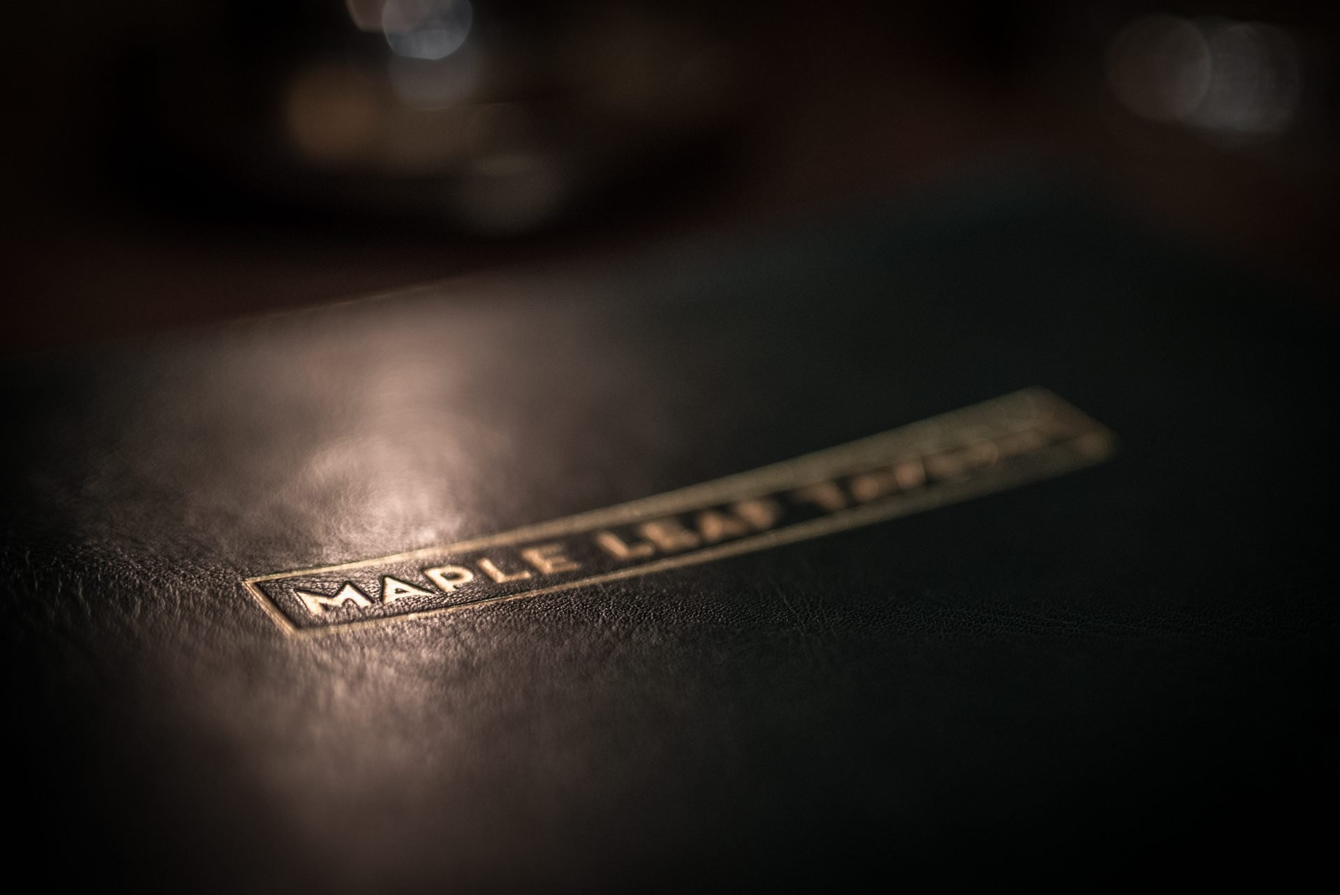 Close-up of a textured black Surface with a brand label reading 'MAPLE LEAF' illuminated softly.