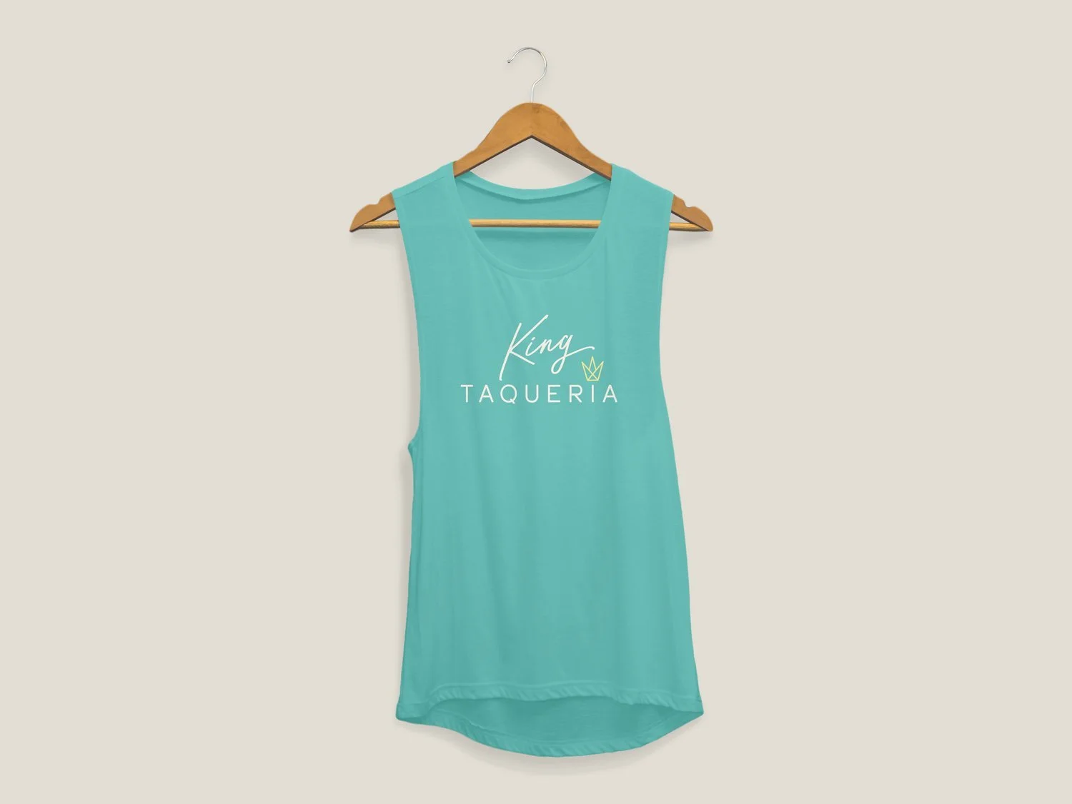 Light blue sleeveless shirt hanging on a wooden hanger against a plain background with the words 'King Taqueria' and a small crown logo printed on it.