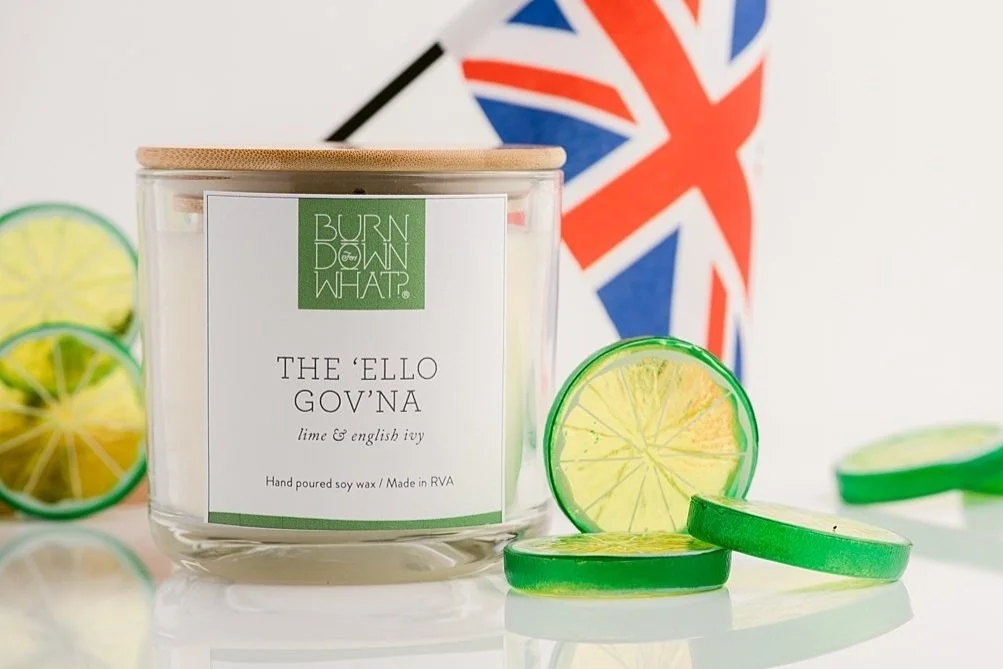 A soy wax candle labeled 'The 'Ello Gov'na' with lime and English ivy fragrance, surrounded by lime and lemon wax melts, and a British flag in the background.