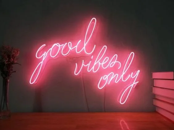 Pink neon sign reading "good vibes only" on a dark wall