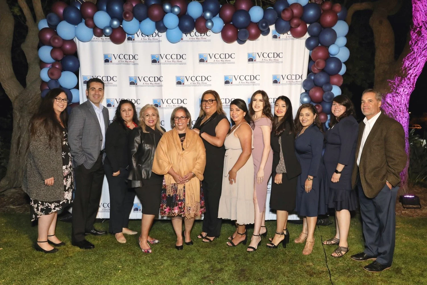 Group of 12 people at awards ceremony in front of photo backdrop.