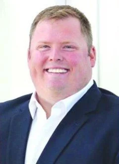 A man with resending hair line wearing a suit.
