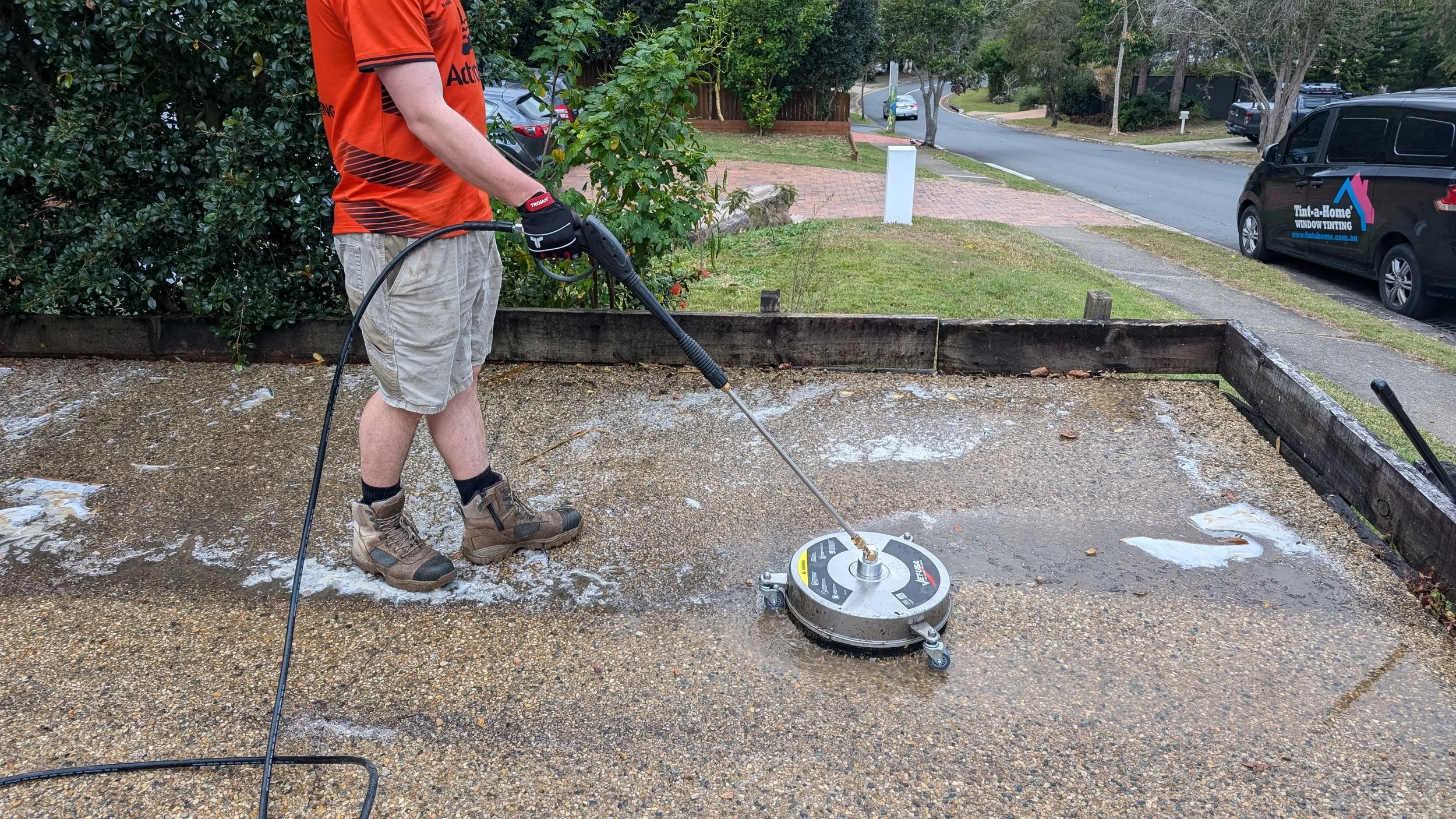 Pressure washing a driveway with a surface cleaner attachment.
