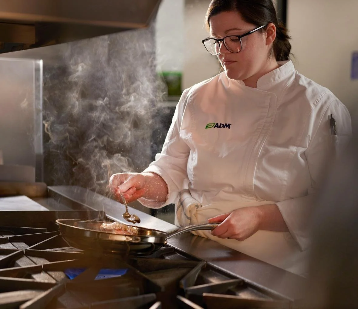 c13female-chef-wearing-white-adm-coat-cooking-with-frying-pan-on-stove-in-culinary-kitchen_lighter.jpg