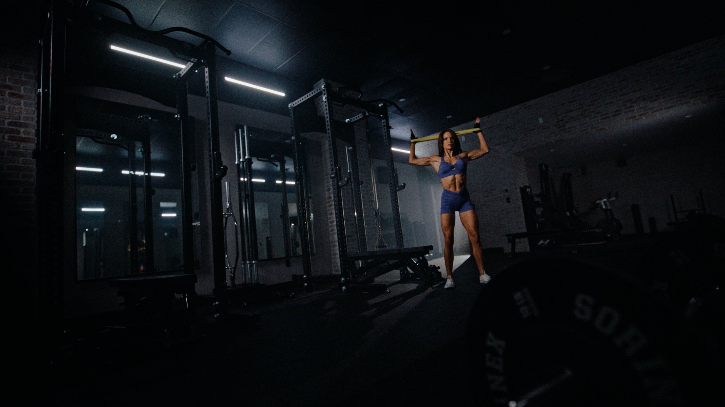 workout commercial solin fitness creator Megan Ewoldsen lifting weights in moody gym