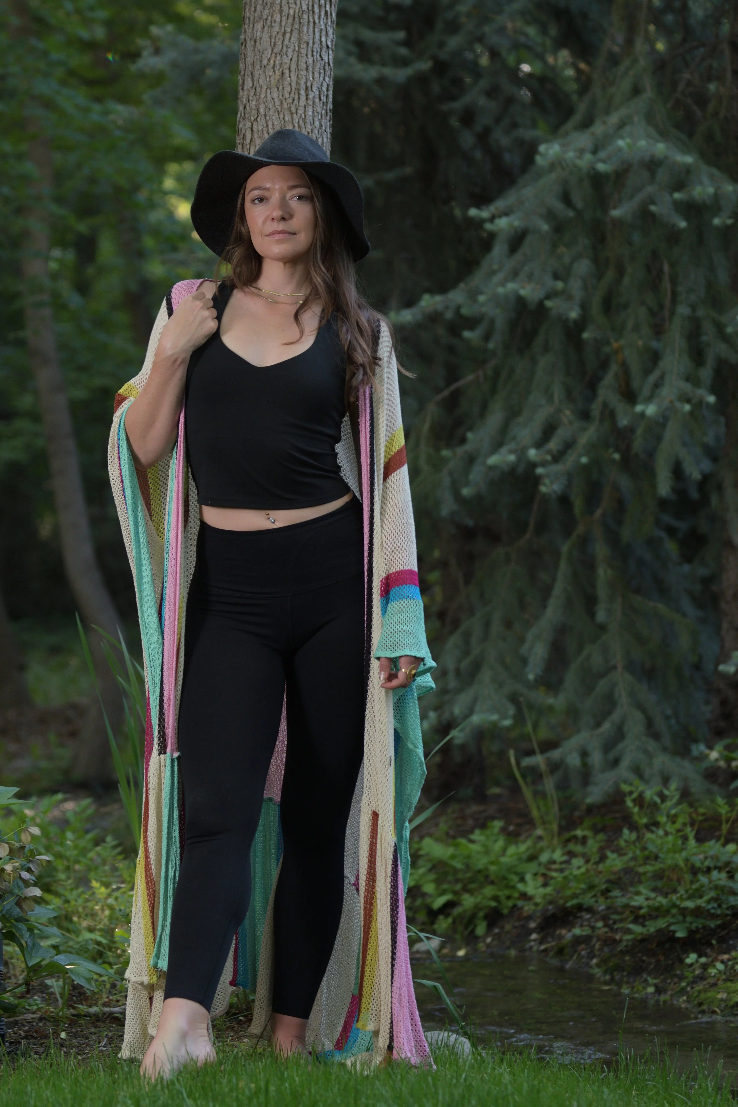 Woman in black with long jacket  next to trees