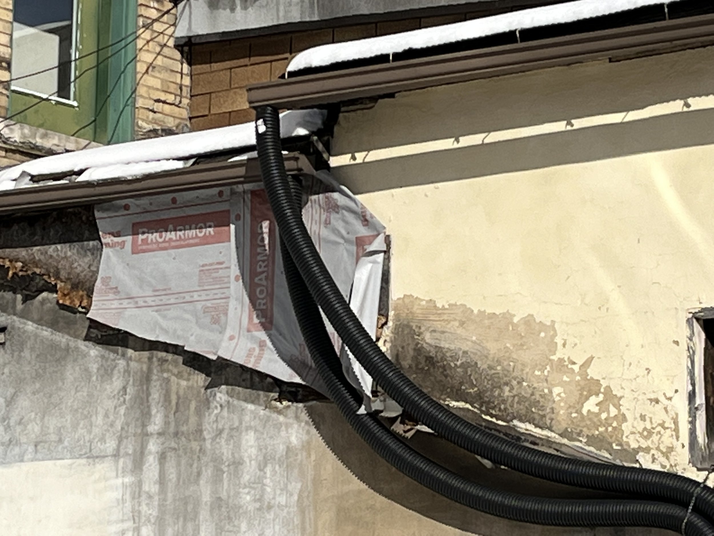 Wall with exposed insulation and black tubing