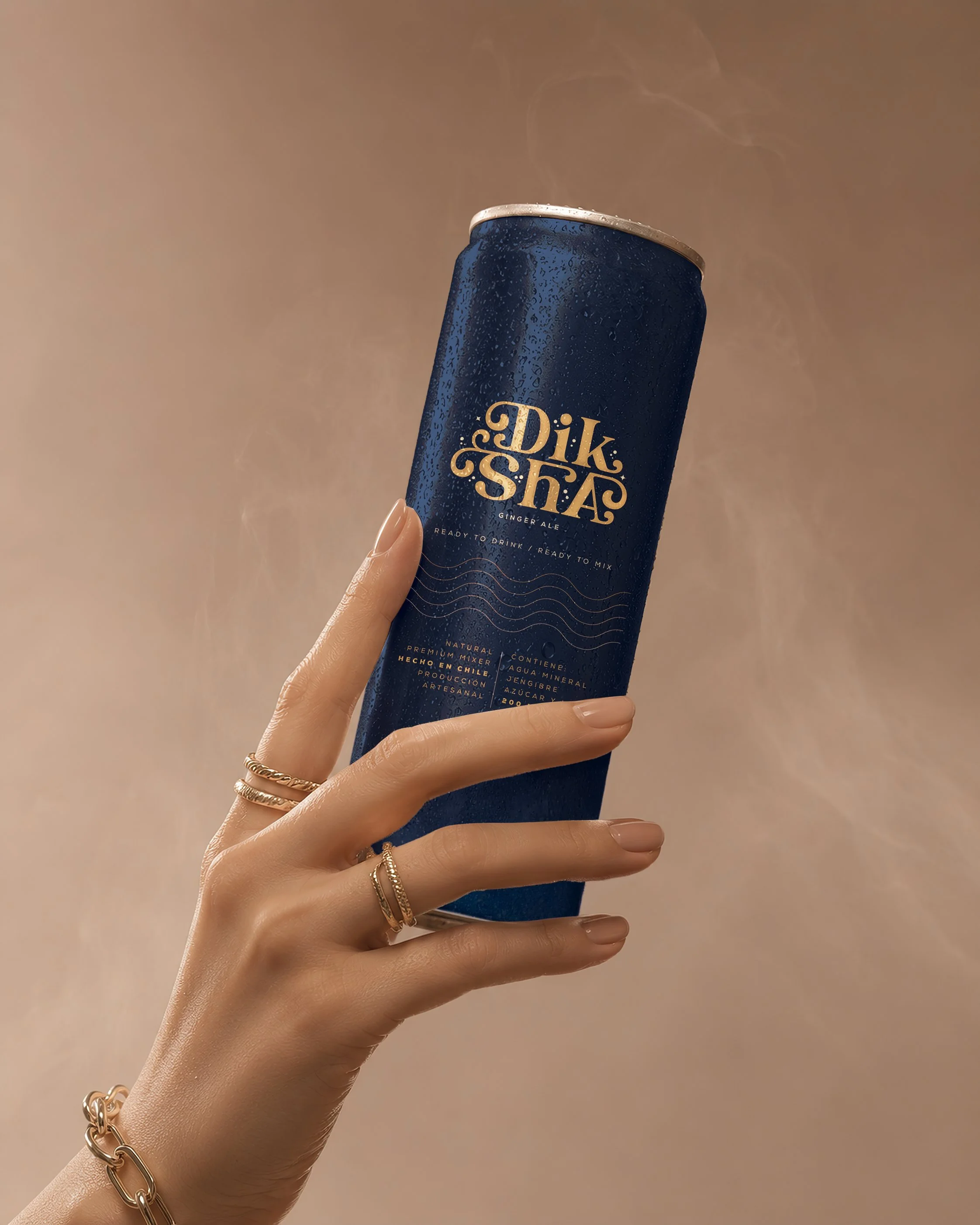 Lata azul con etiqueta que dice 'Dikshas Ginger Ale' siendo sostenida por una mano con varias pulseras doradas, con vapor saliendo de la parte superior, fondo beige.