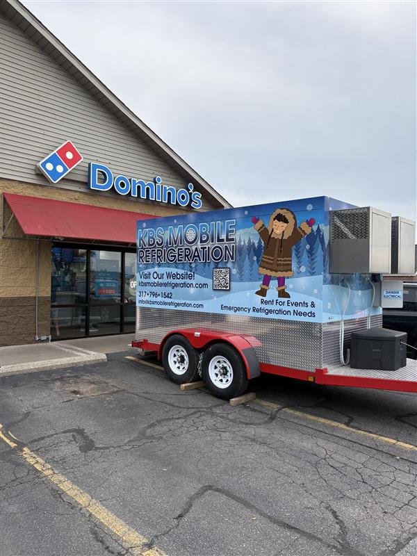 A mobile refrigeration cooler unit for KBS Mobile Refrigeration with a winter theme outside Domino's pizza. A cartoon girl wearing a brown coat and pink gloves, and contact information including a website and phone number. Serving Indiana.
