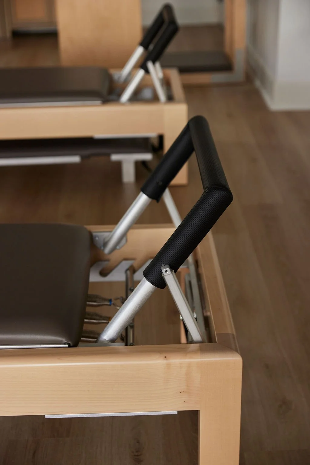 Close-up of wooden seating with black armrests and metal supports, in an auditorium or lecture hall.