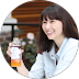 Person smiling and holding a beverage bottle outdoors.