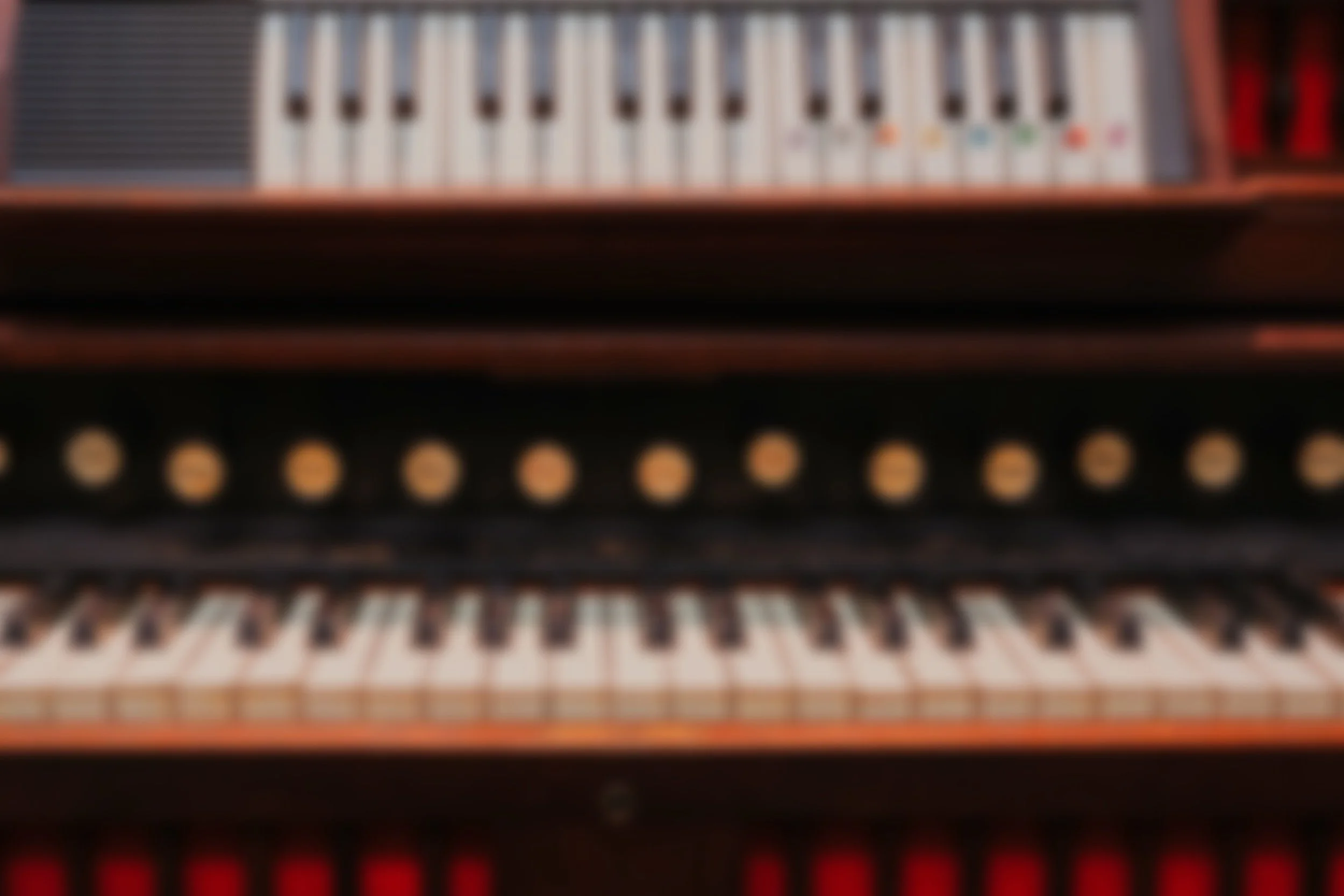 Blurred close-up of a piano, showing keys and parts of the wooden frame.