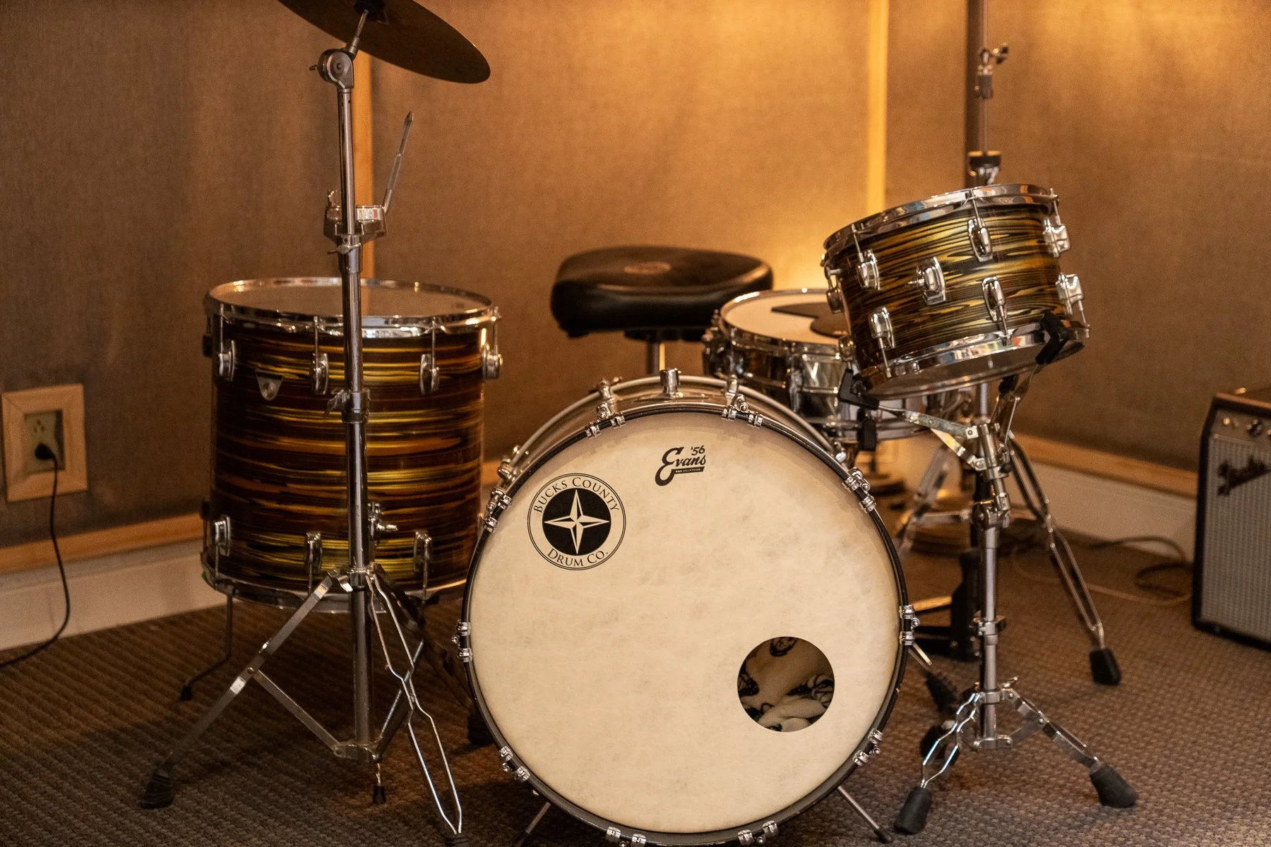 A drum set with a bass drum, two mounted toms, a snare drum, and cymbals in a music studio.